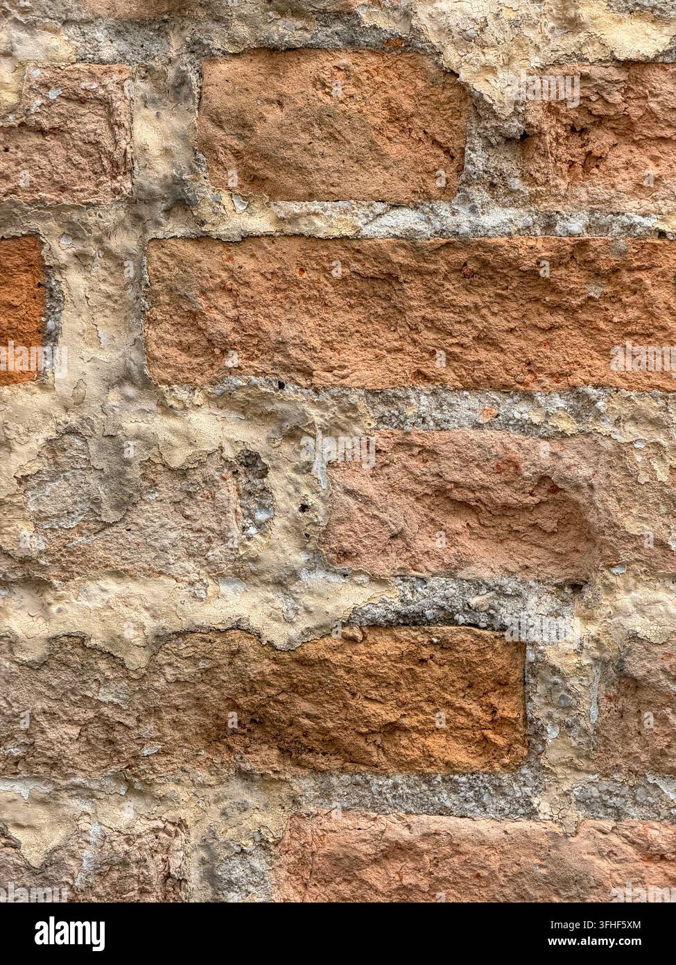 gros plan d'un vieux mur de briques rouges exposé avec un mortier irrégulier, un plâtre fissuré et une texture de maçonnerie naturellement érodée. Banque D'Images