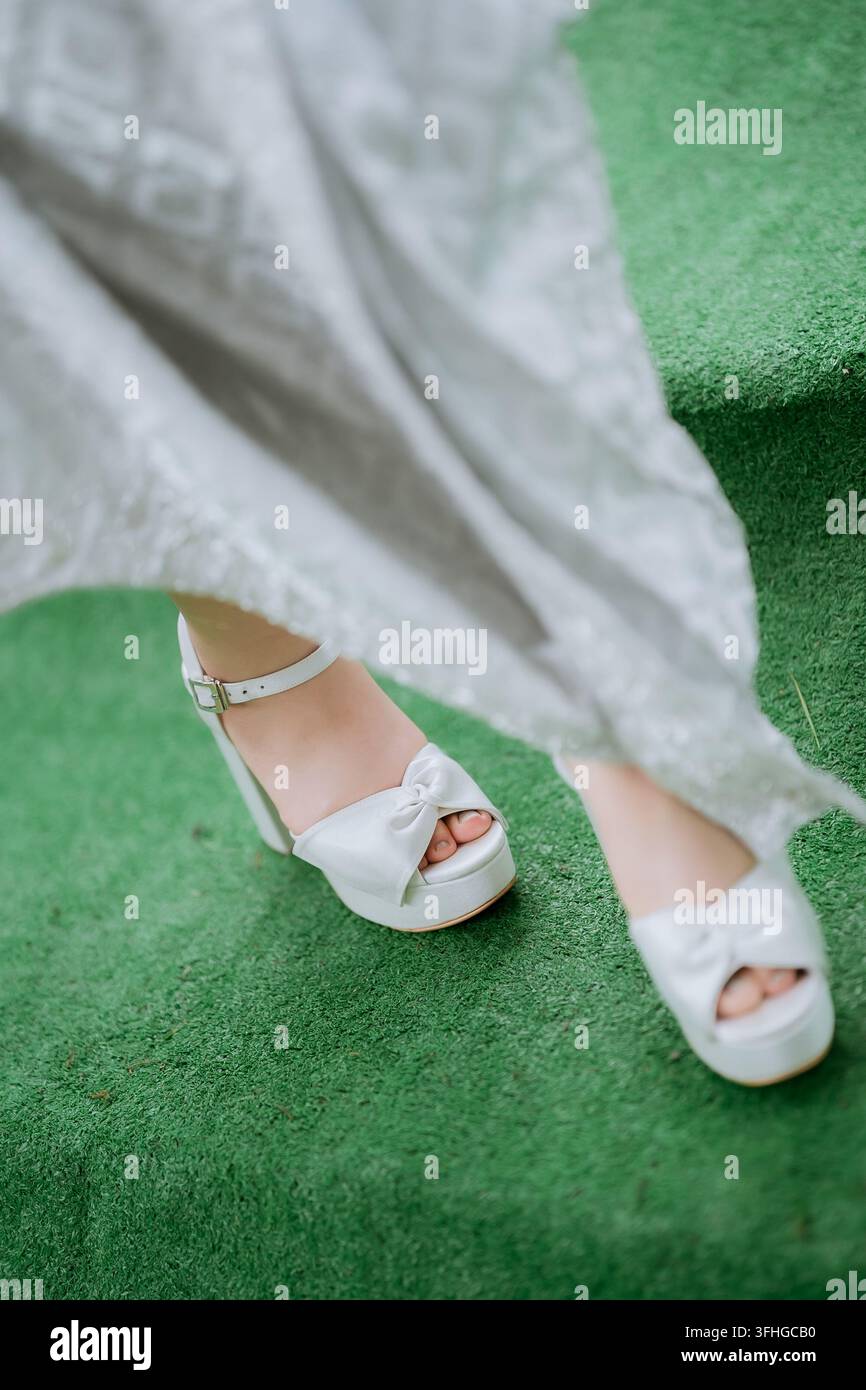 Sandales blanches élégantes à plate-forme sur des marches en gazon artificiel vert Banque D'Images