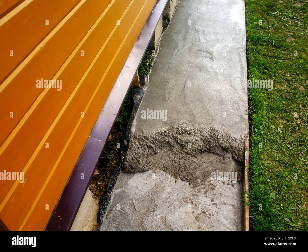 Verser du béton pour créer un chemin près d'une maison de campagne, en utilisant ses propres mains. Banque D'Images