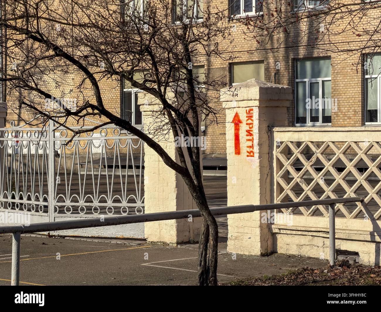 Un symbole de navigation directionnel est marqué sur un mur de maçonnerie pointant vers une installation de sécurité, capturant une atmosphère urbaine tendue concernant les zones de conflit Banque D'Images