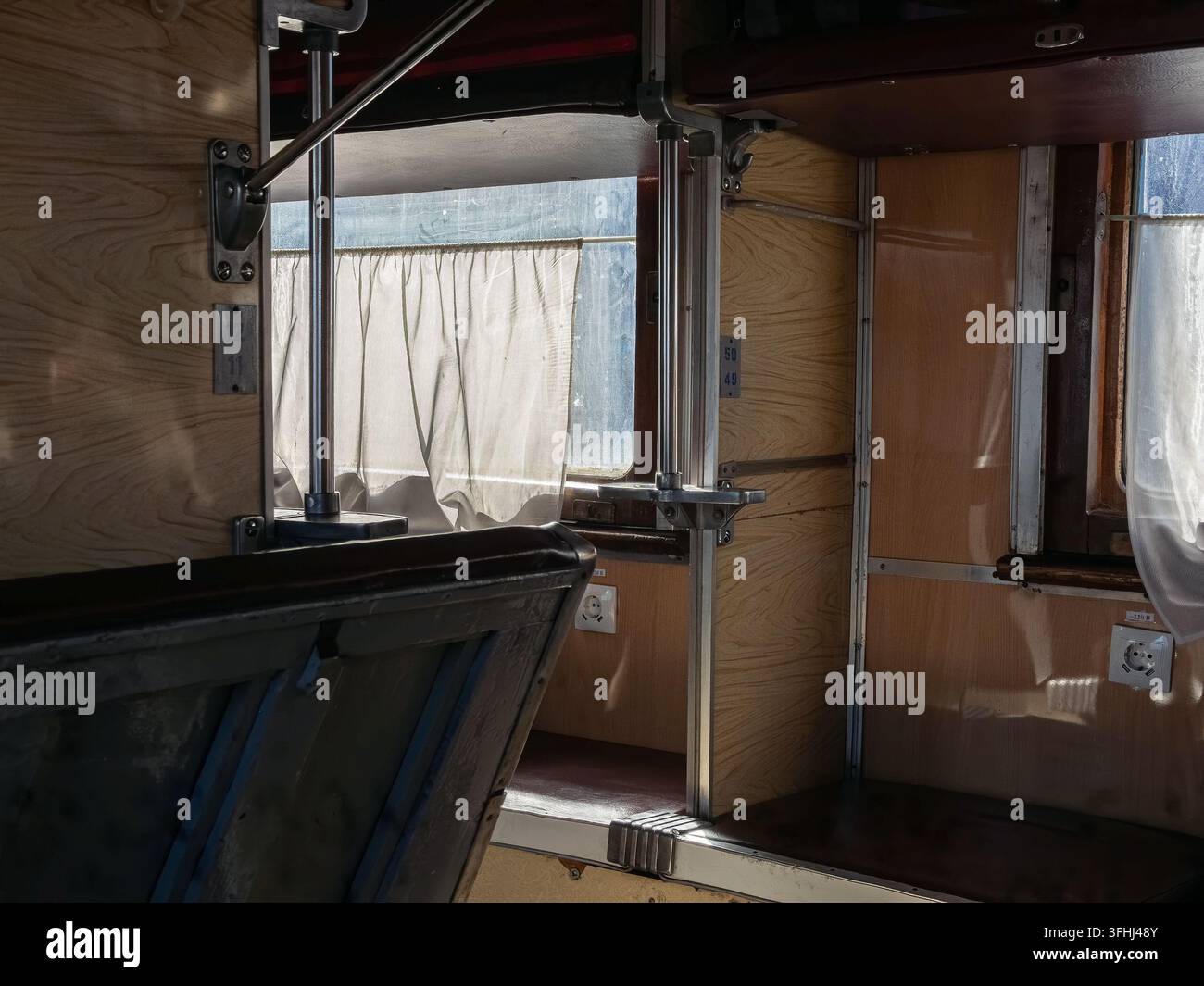 Les couchettes vides d'un vieux wagon ferroviaire présentent des textures de bois usées et des supports métalliques, évoquant l'essence classique de la solitude et de l'attente Banque D'Images