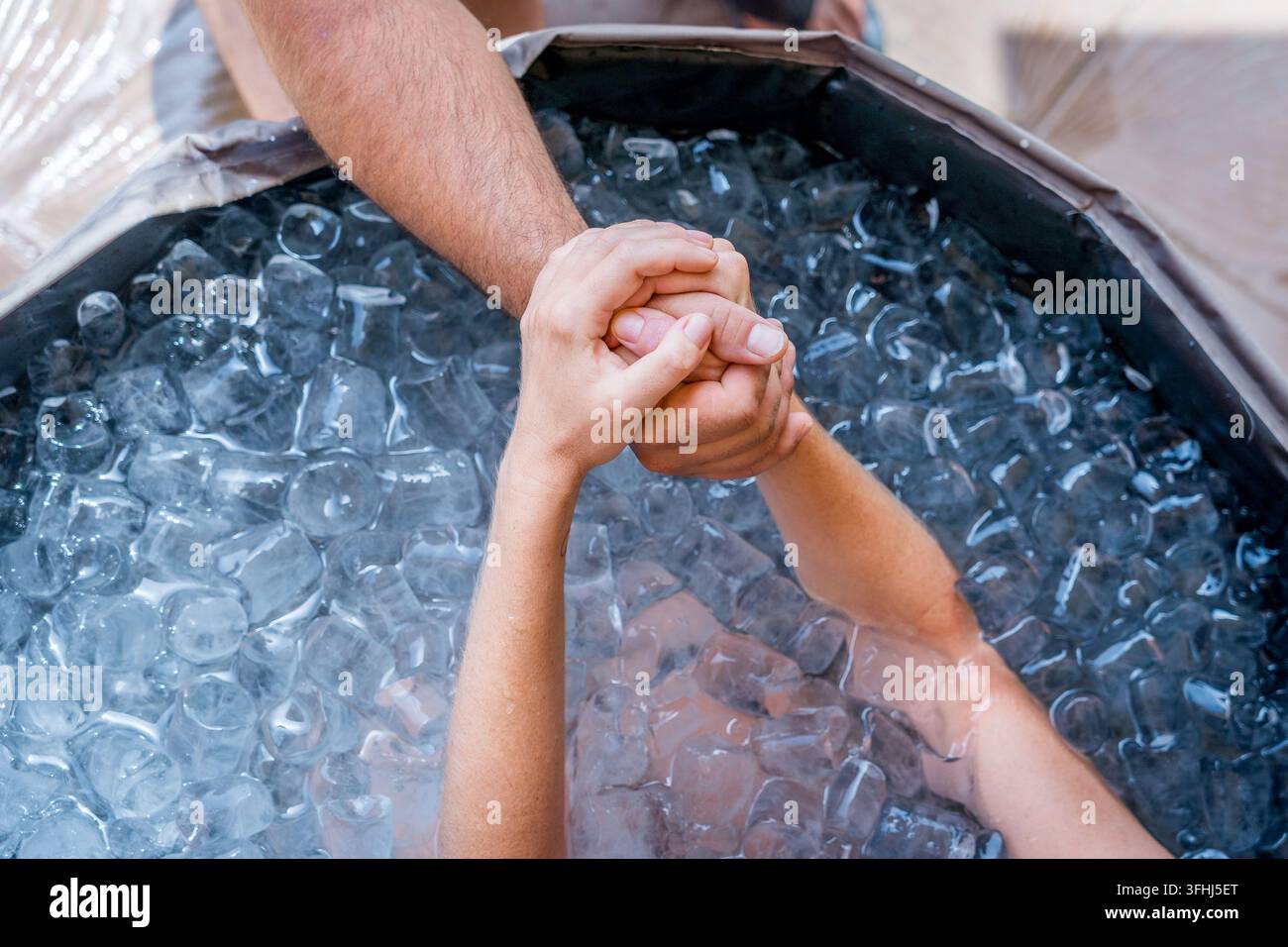 Gros plan des mains d'une personne prenant un bain glacé ou un plongeon froid selon la méthode Wim Hof dans une baignoire circulaire pour la récupération musculaire et mentale Banque D'Images