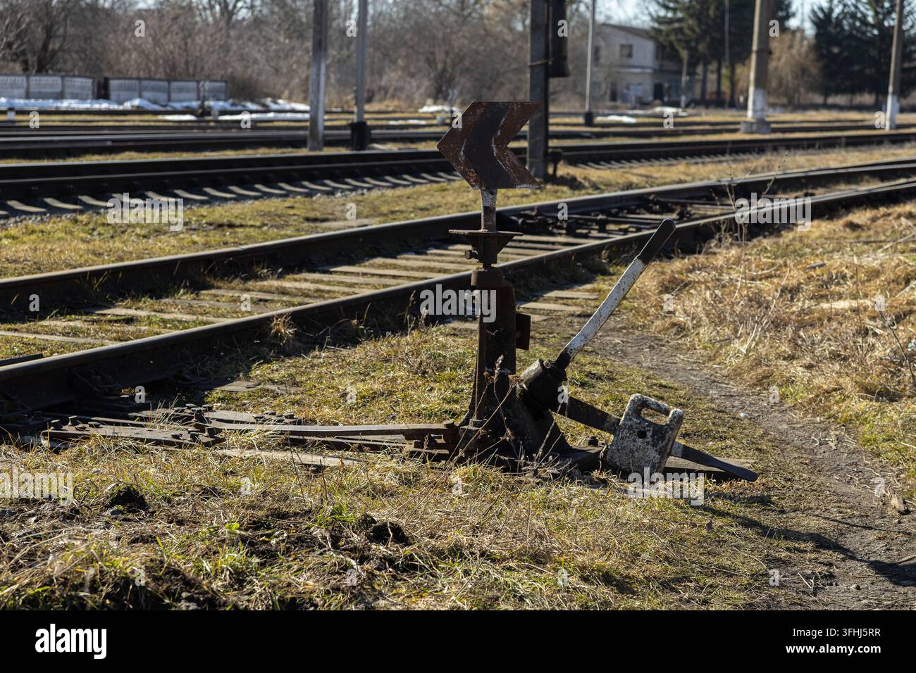 Un vieux levier en fer contrôle un aiguillage le long d'une voie ferroviaire rurale, illustrant l'infrastructure mécanique classique utilisée pour guider les locomotives Banque D'Images