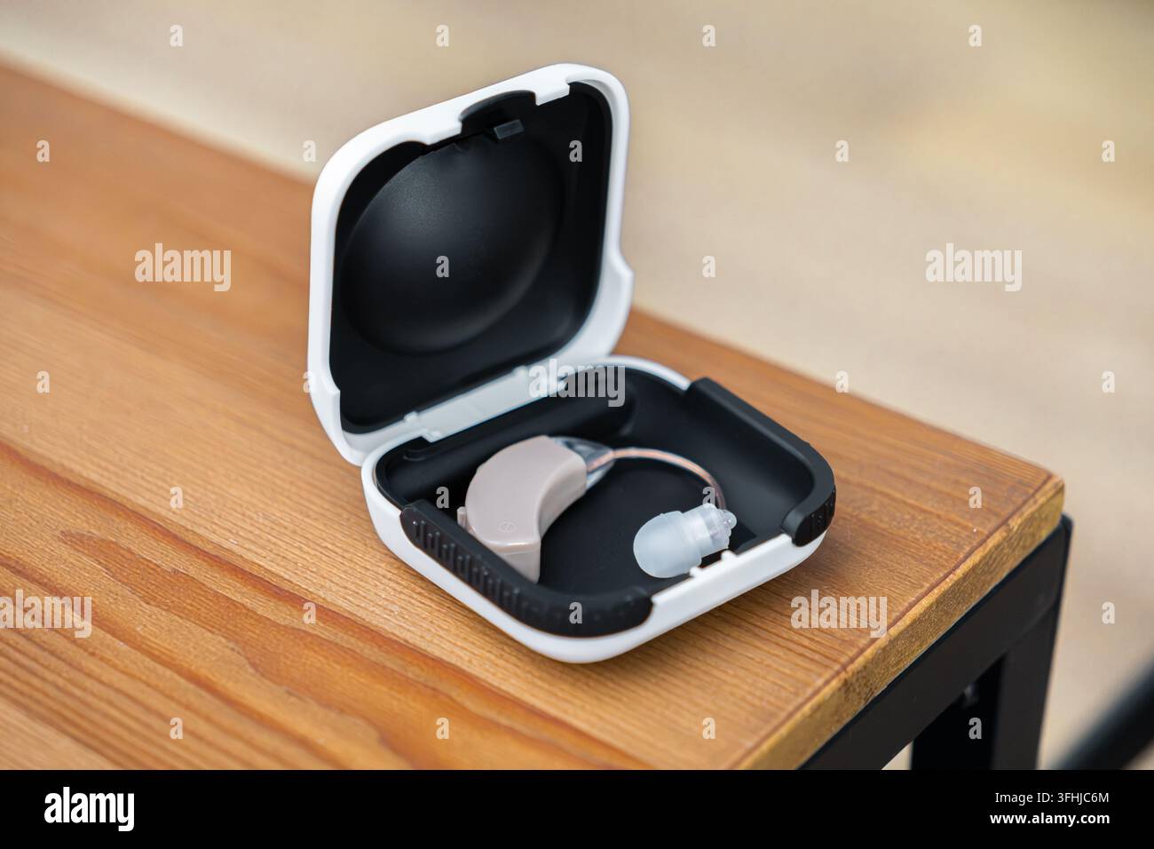 L'appareil auditif médical est rangé dans son élégant conteneur de stockage portable sur une surface en bois, offrant une représentation visuelle claire de la modernité Banque D'Images