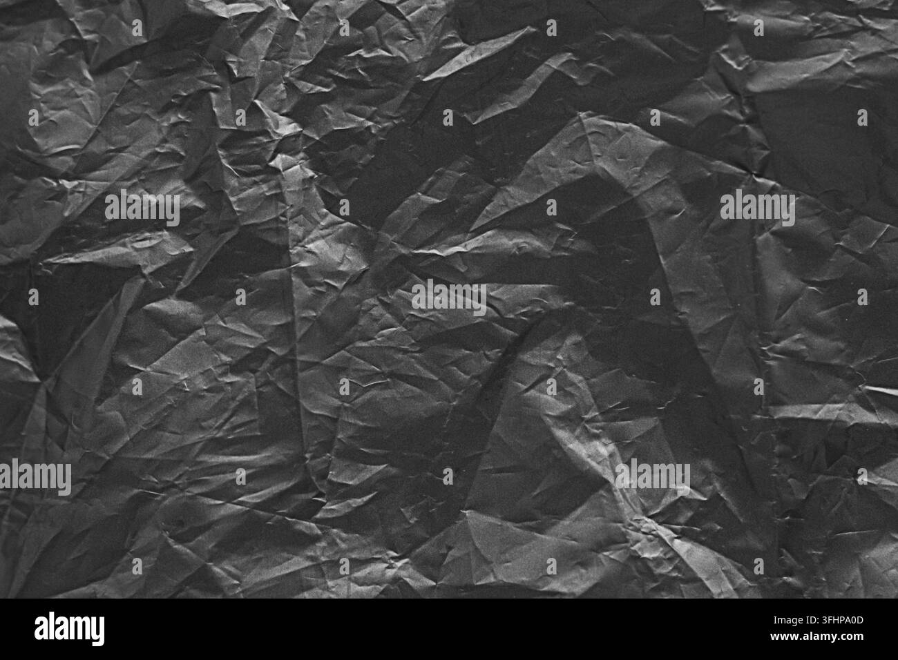 Texture de papier noir froissé avec surface plissée et ombre dramatique pour fond grunge Banque D'Images