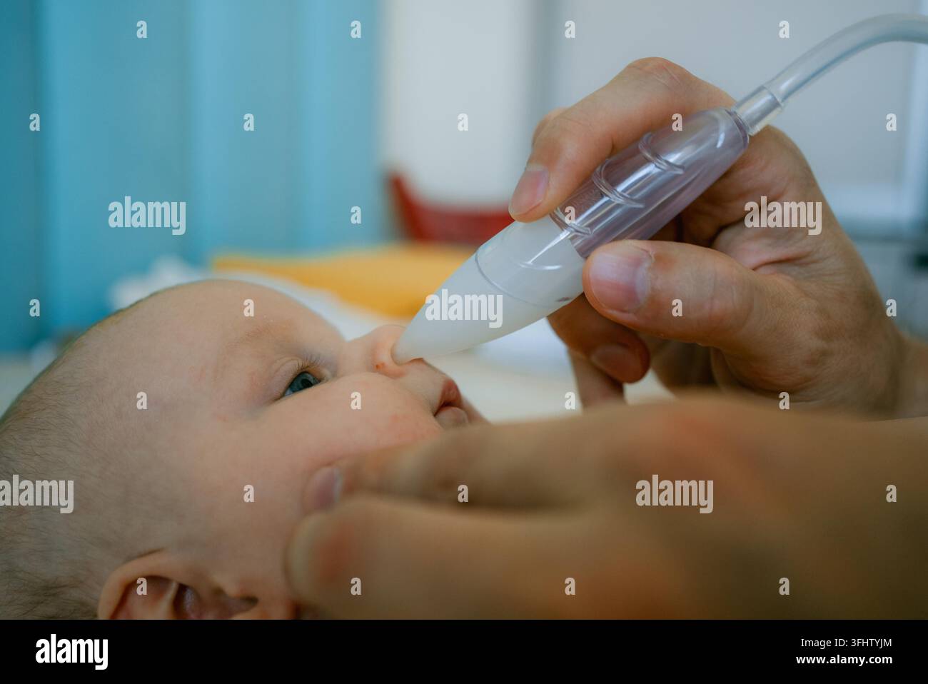 Un parent utilise soigneusement un aspirateur nasal manuel pour retirer la mucus du nez bouché d'un bébé, soutenant la santé respiratoire du nourrisson et fournissant des soins essentiels au nouveau-né en cas de congestion Banque D'Images