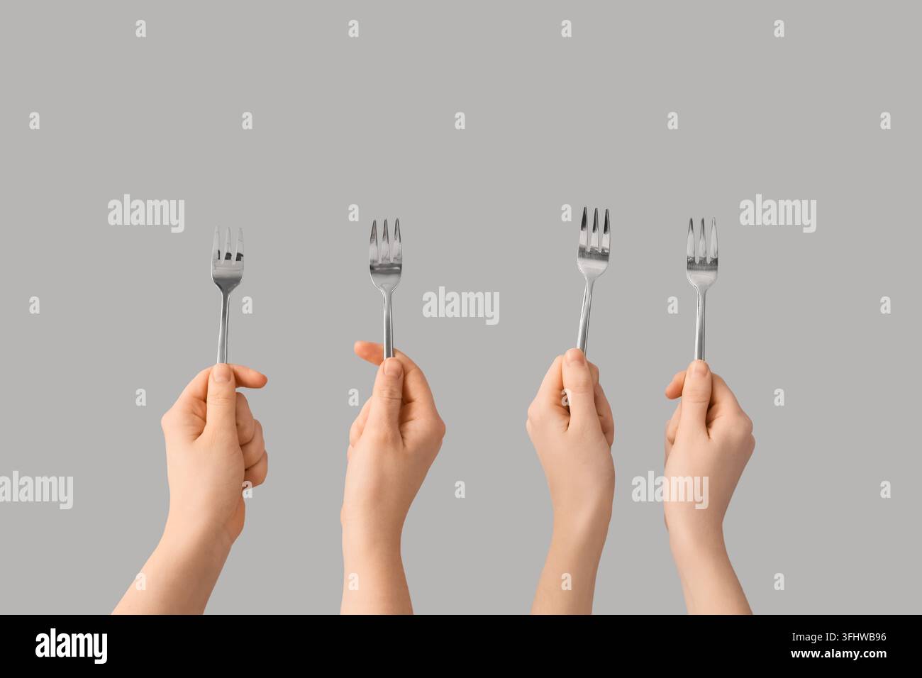 Diversité et inclusion : plusieurs mains tenant des fourchettes ensemble comme symbole de travail d'équipe, de collaboration communautaire et d'expérience culinaire partagée Banque D'Images