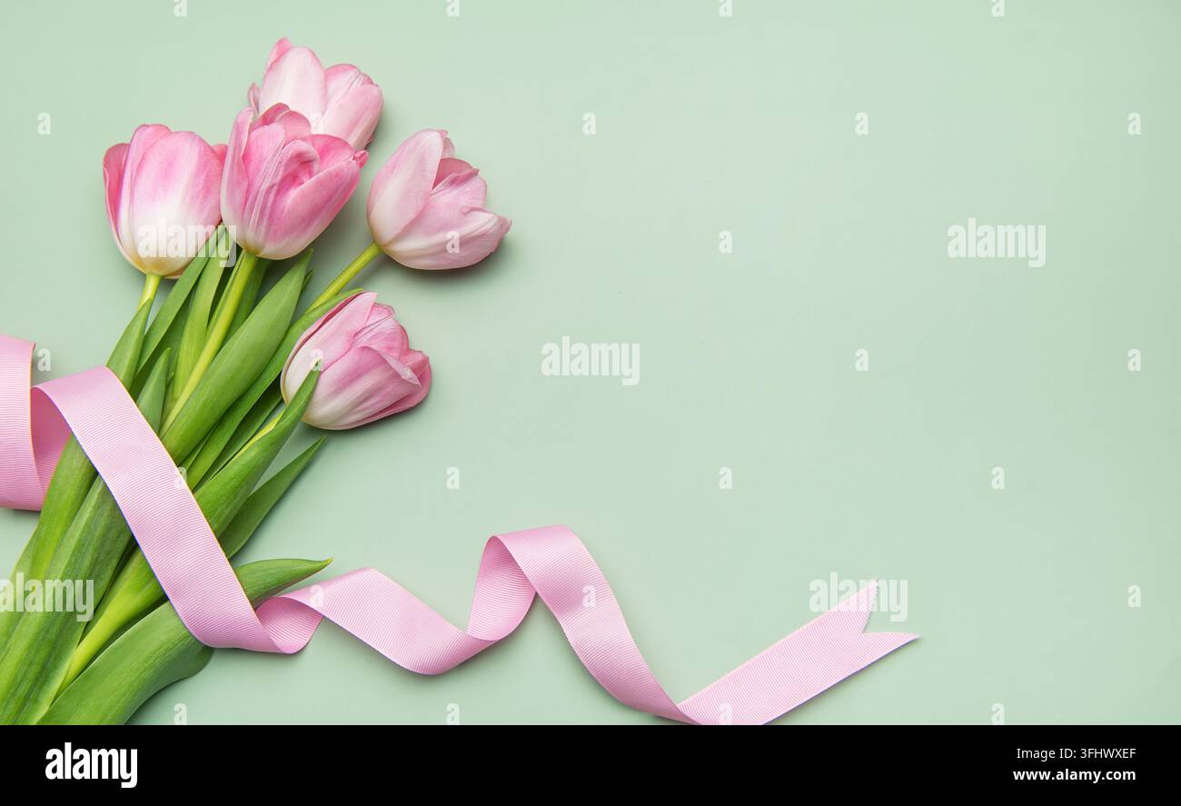 Tulips roses avec ruban sur fond vert pastel pour les vacances de printemps Banque D'Images