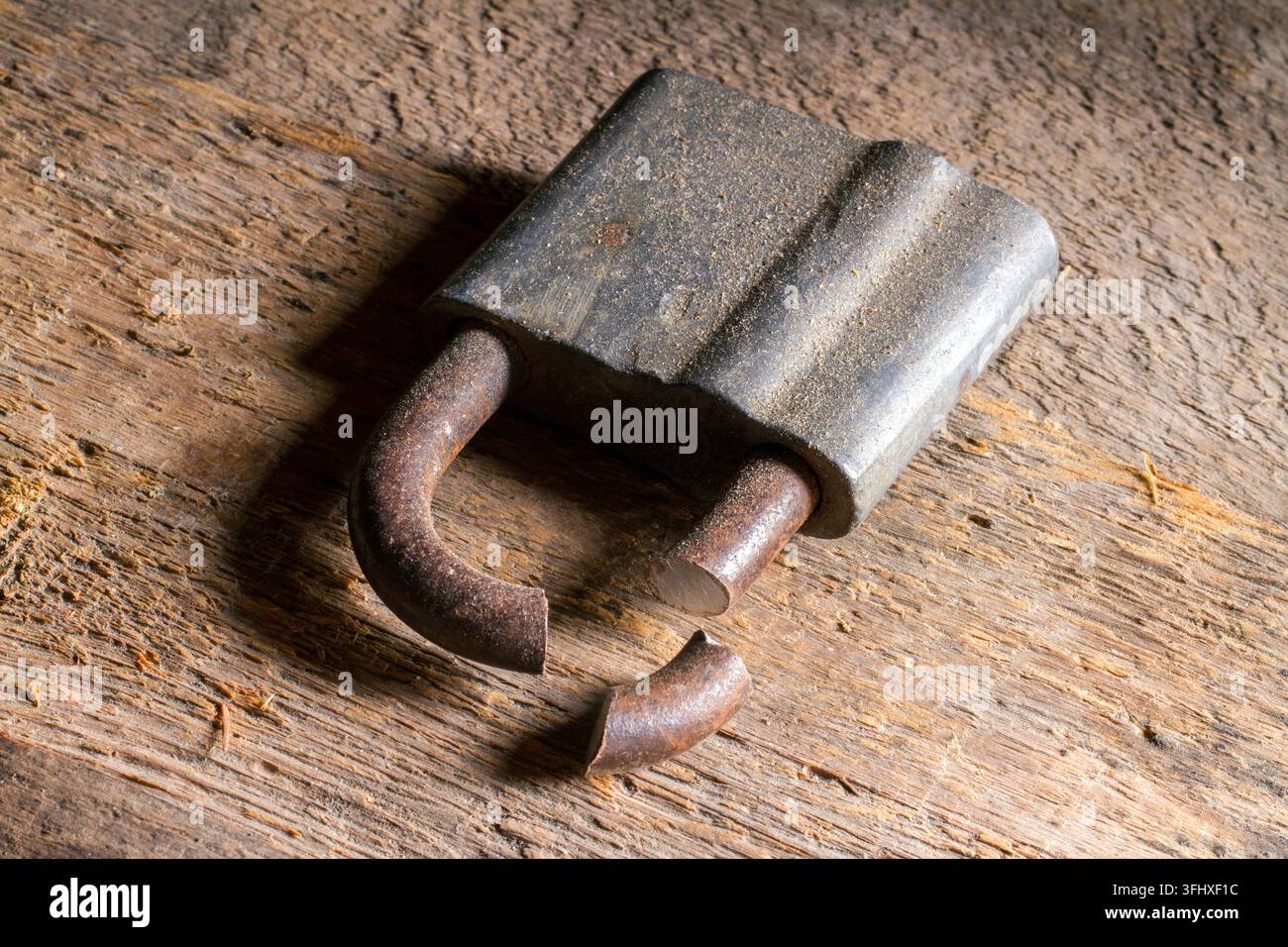 Un vieil anneau scié sur une surface en bois. Un cadenas cassé. Banque D'Images