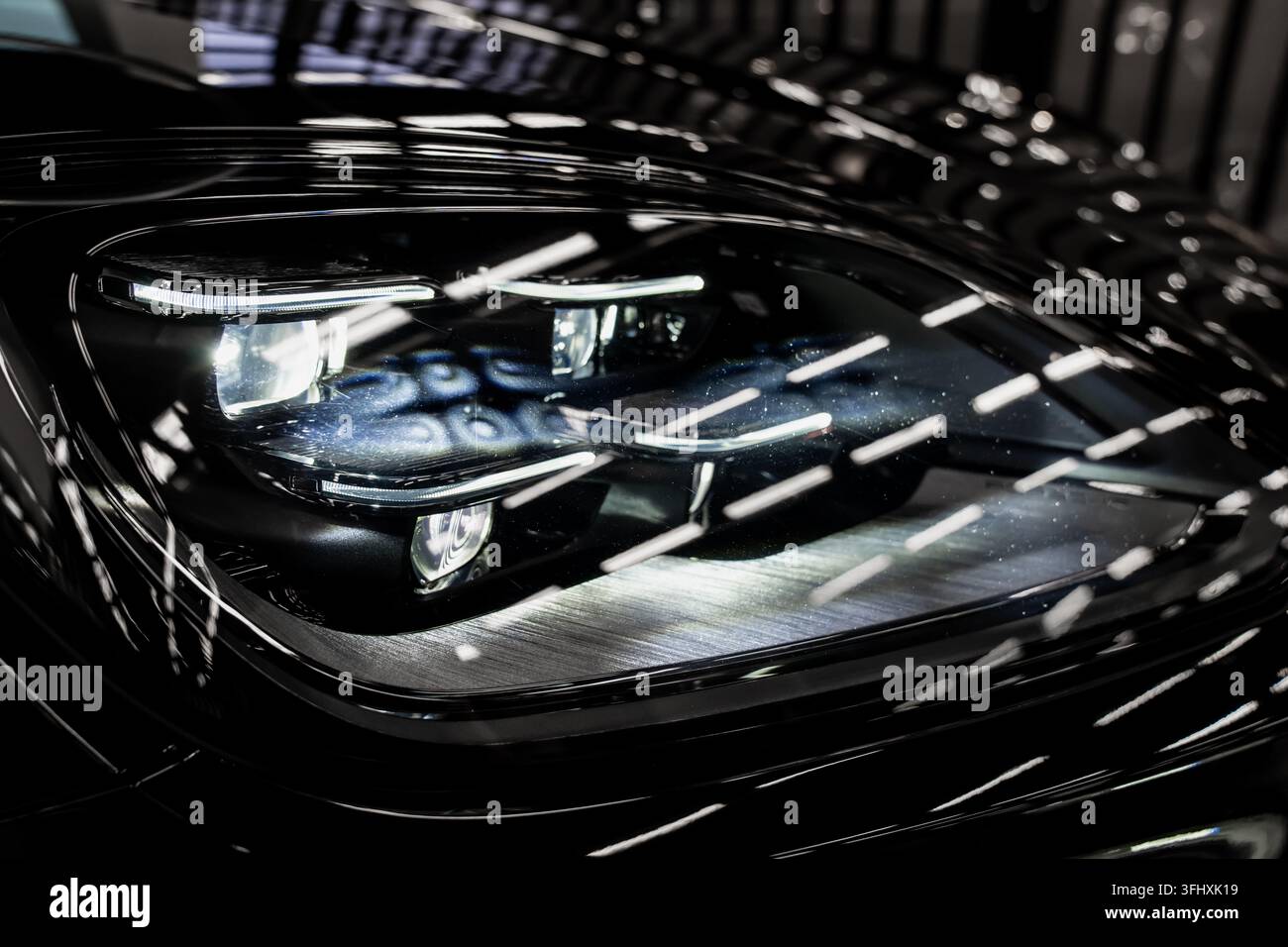 Phare de voiture avec plusieurs projecteurs illuminés et bandes LED intégrées, montrant les composants optiques automobiles utilisés pour l'éclairage routier et le véhicule Banque D'Images