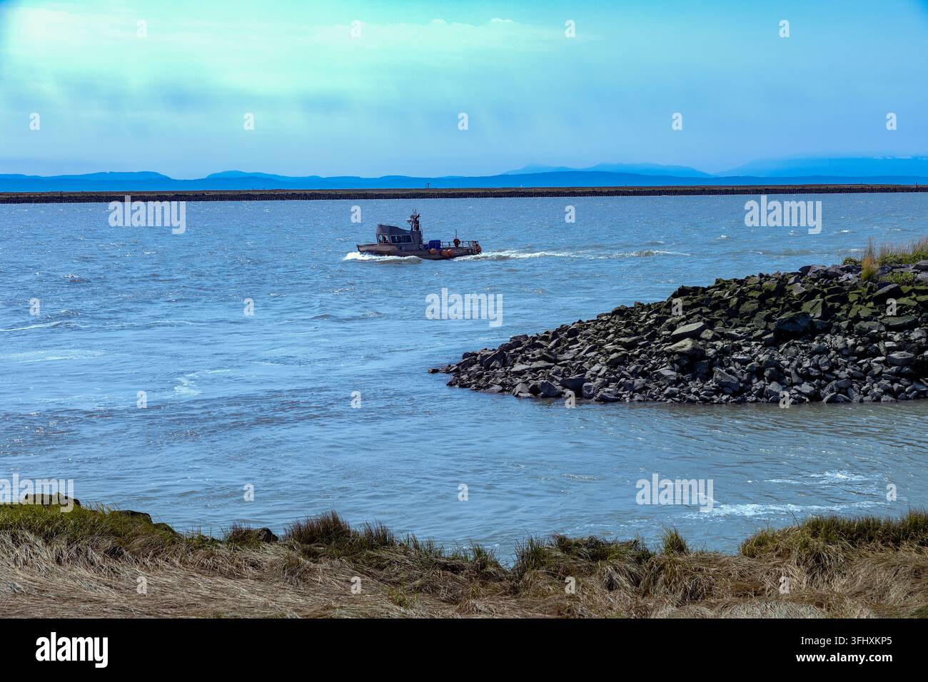 Péniche traverse une vaste étendue d'eau bleue sous un ciel nuageux, parc Garry Point, Richmond, Colombie-Britannique, Canada Banque D'Images