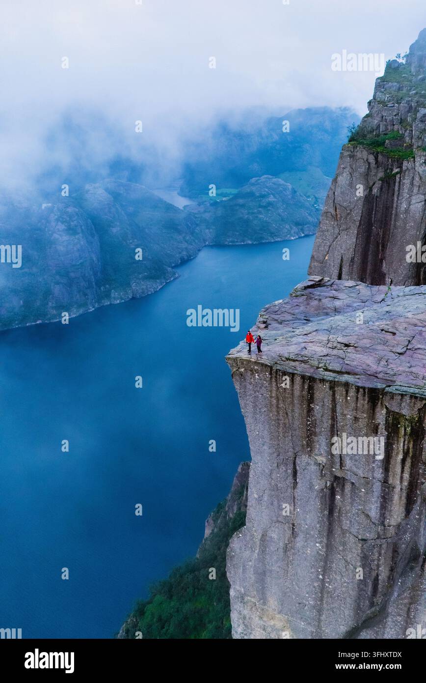 Vue imprenable depuis la falaise de Preikestolen en Norvège avec des aventuriers explorant le bord Banque D'Images