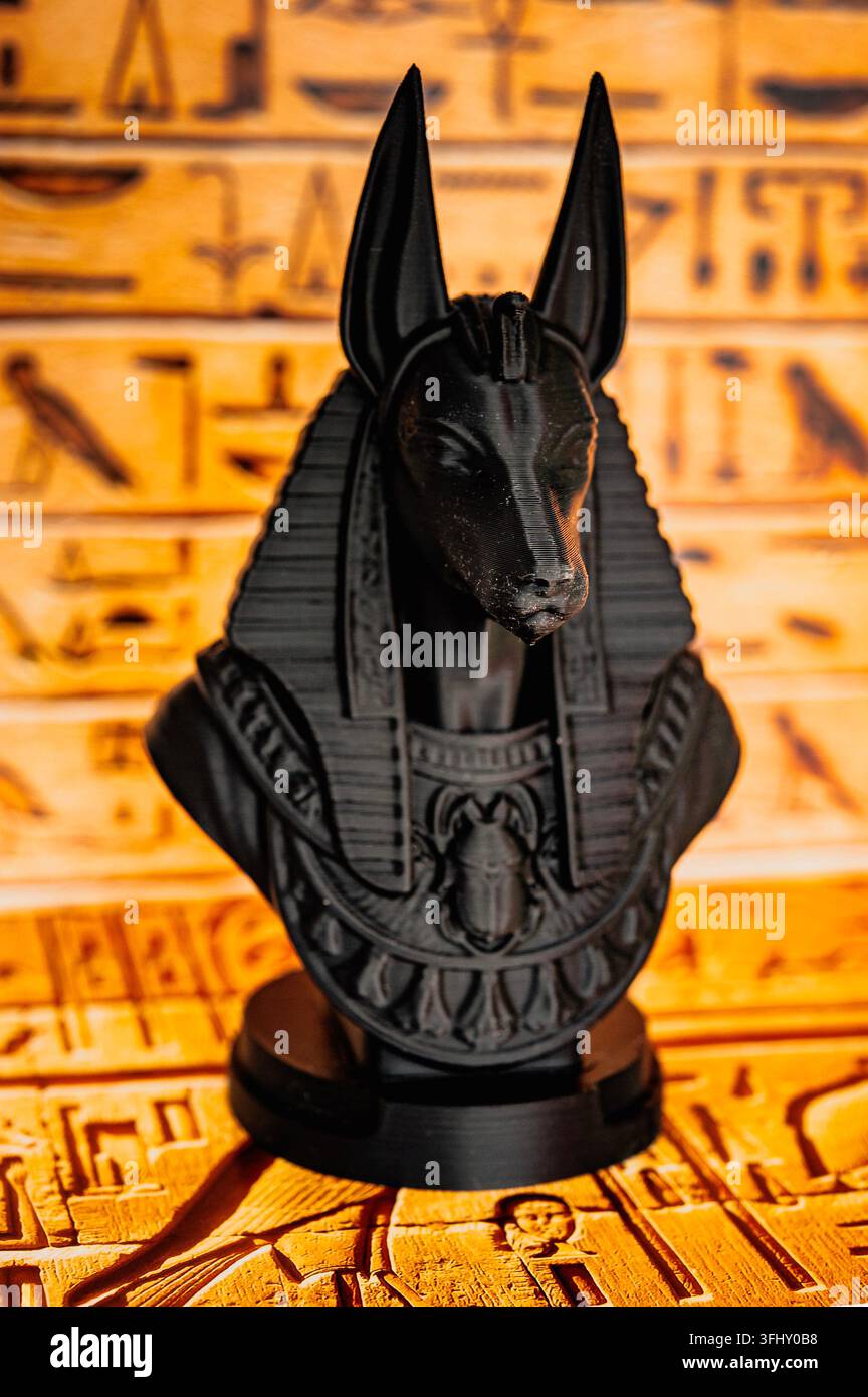 Statue d'Anubis affichée devant des hiéroglyphes égyptiens lumineux, évoquant l'Égypte ancienne, la mythologie, les croyances funéraires et l'archéologie Banque D'Images