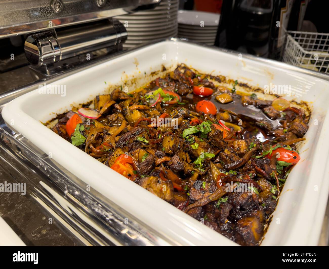 Viande rôtie glacée mélangée à des légumes frais dans un plateau chauffant d'hôtel, créant une présentation de repas chaud appétissante pour les services de catering professionnels Banque D'Images