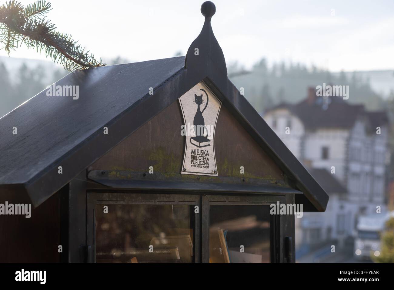 Szklarska Poręba, Pologne – 17 décembre 2025 : Une station d'échange de livres en bois d'extérieur arbore un logo de chat, promouvant l'alphabétisation et la lecture gratuite parmi Banque D'Images
