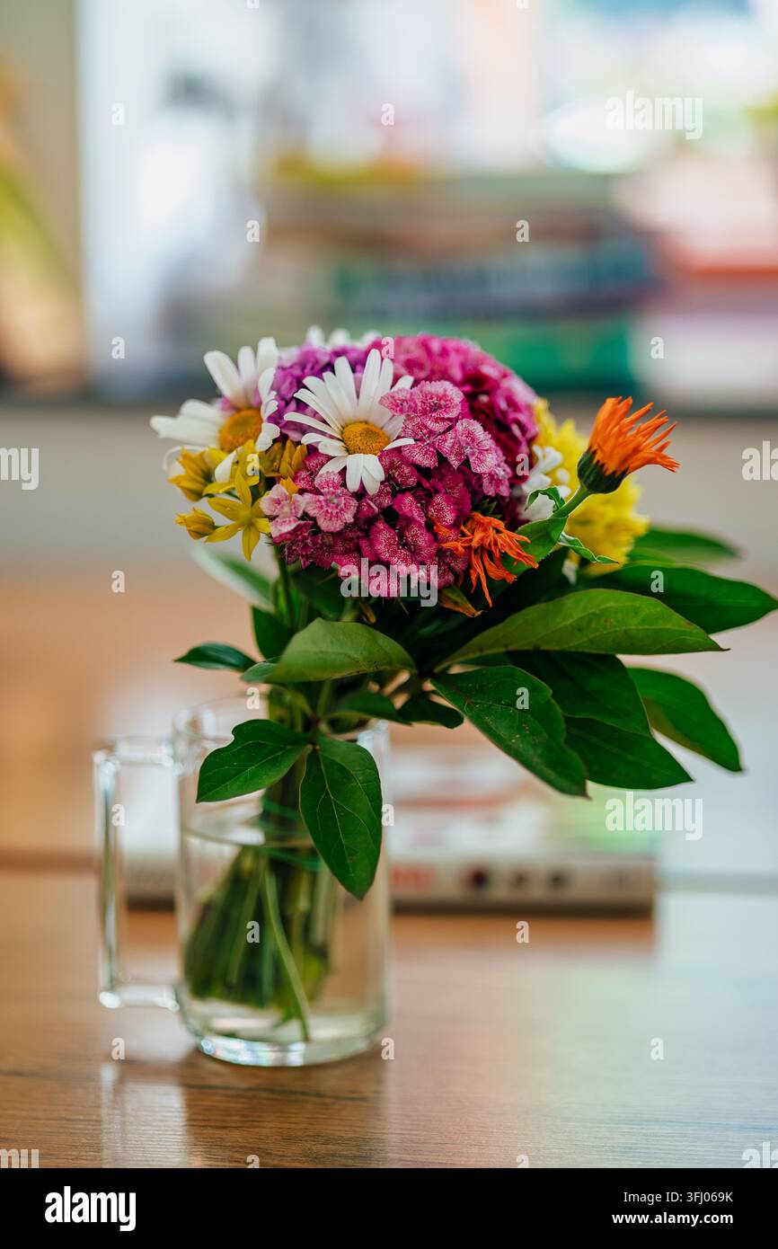 Bouquet de fleurs sauvages éclatant dans une tasse en verre transparent sur une table Banque D'Images