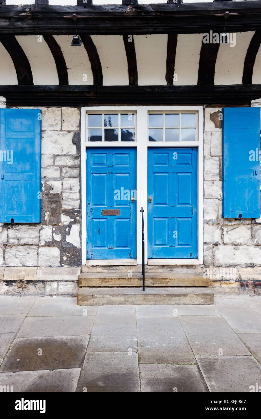 Portes bleues et volets bleus sur une façade en pierre avec poutres en bois et marches York Yorkshire UK Banque D'Images