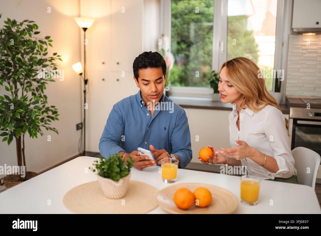 Jeune couple prenant le petit déjeuner et parlant dans la cuisine Banque D'Images