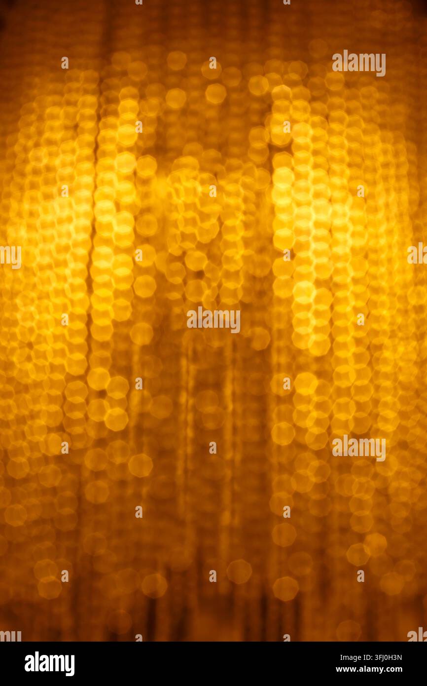 Bokeh de perles de cristal de lustre ambre doré flou avec lueur chaude en composition verticale Banque D'Images