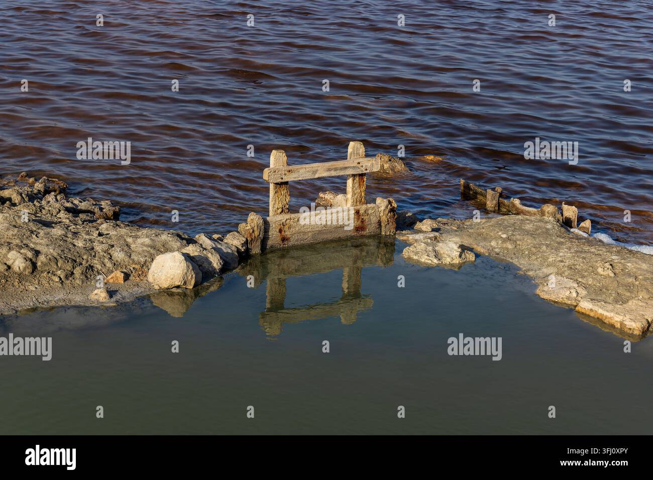 écluse en bois patiné au bord d'une lagune saline côtière entourée d'eaux peu profondes et d'un paysage naturel de marais. Banque D'Images