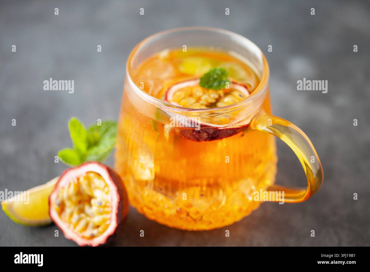 Thé glacé aux fruits. Boisson estivale rafraîchissante avec sirop, fruit de la passion, citron vert, menthe et glace. Verre avec boisson froide et saine Banque D'Images