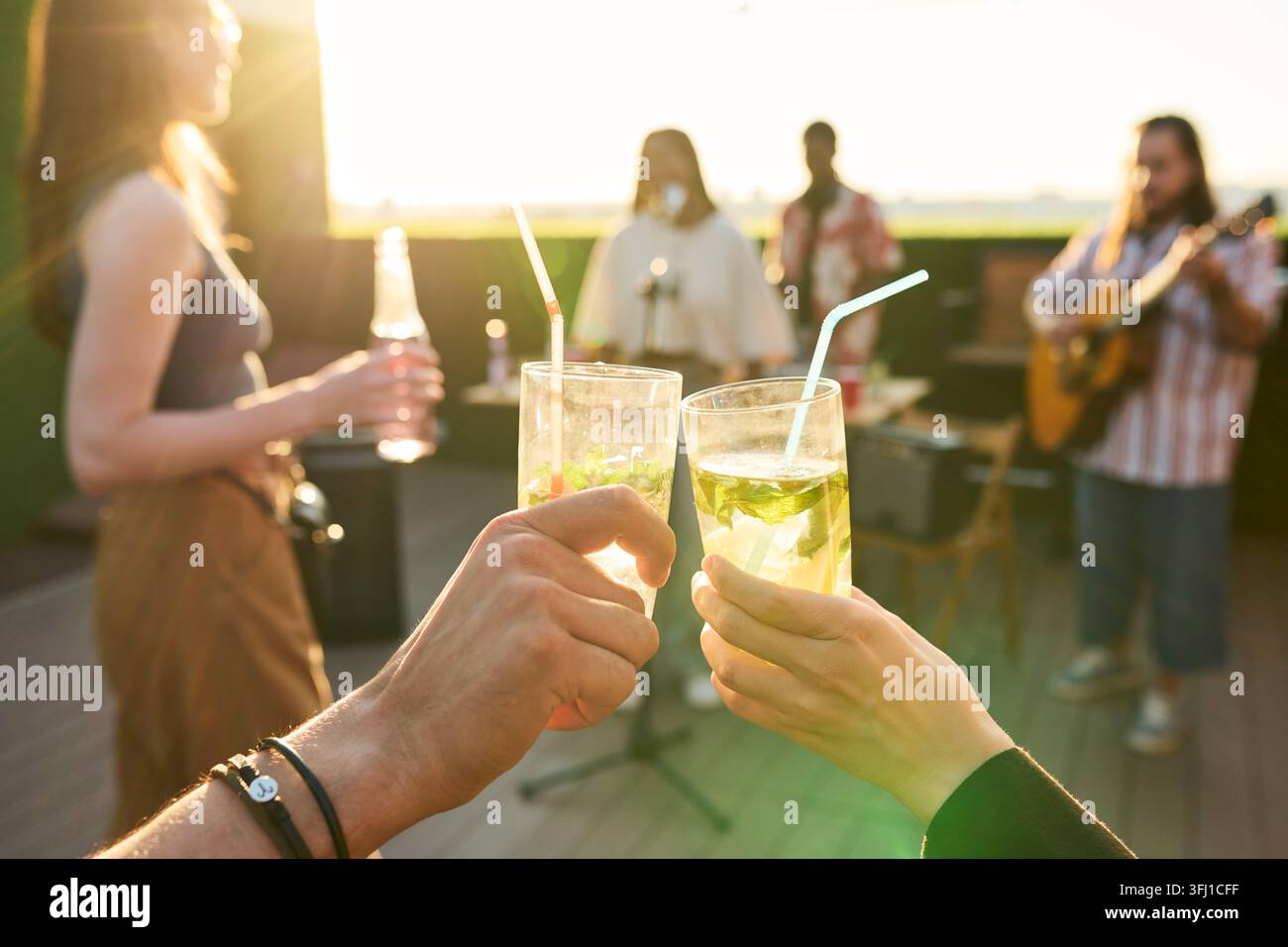 Amis portant un toast avec des cocktails lors d'une fête d'été sur le toit Banque D'Images