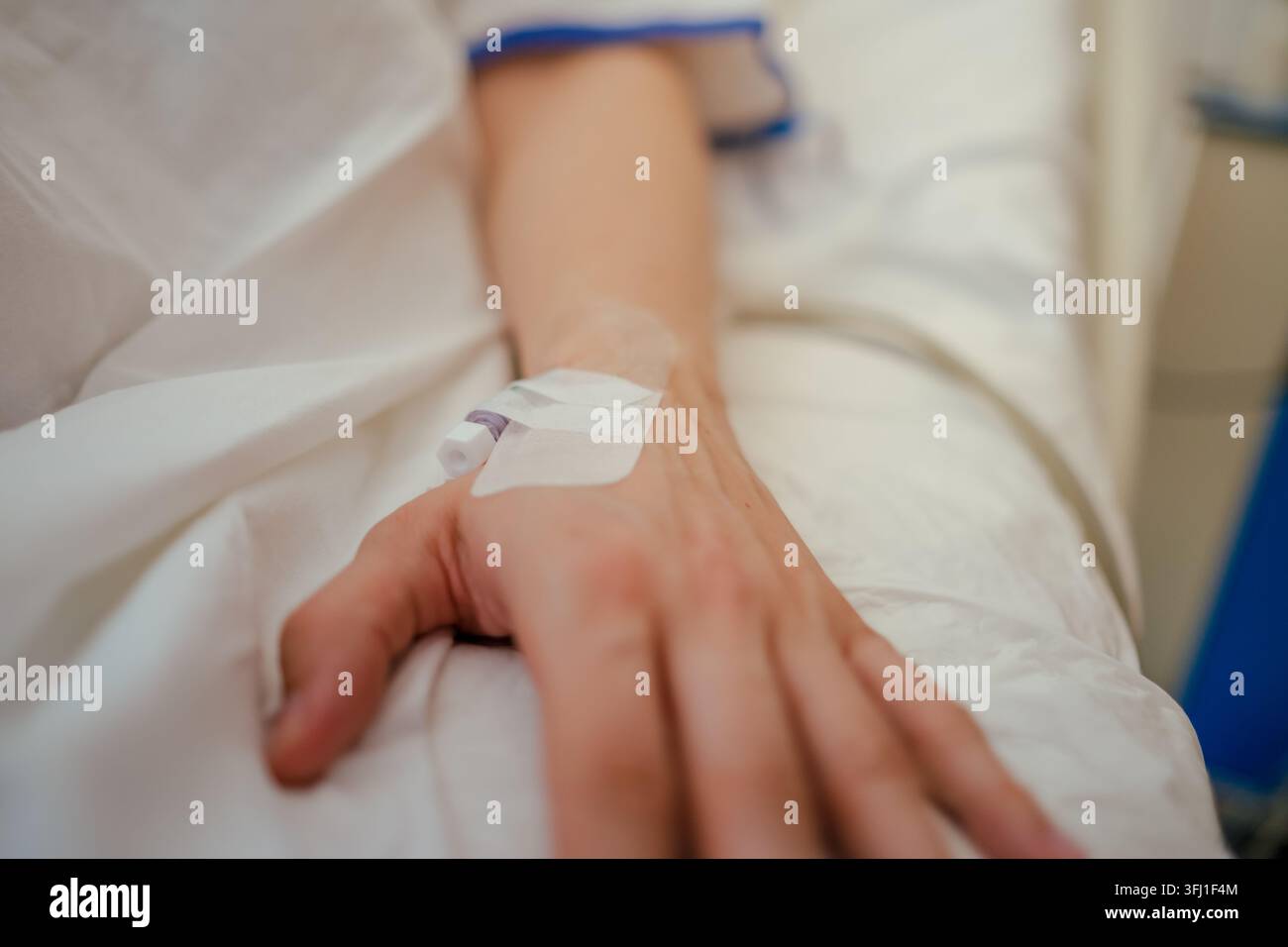 Main de patient avec un cathéter IV sur un drap d'hôpital blanc pendant le traitement Banque D'Images