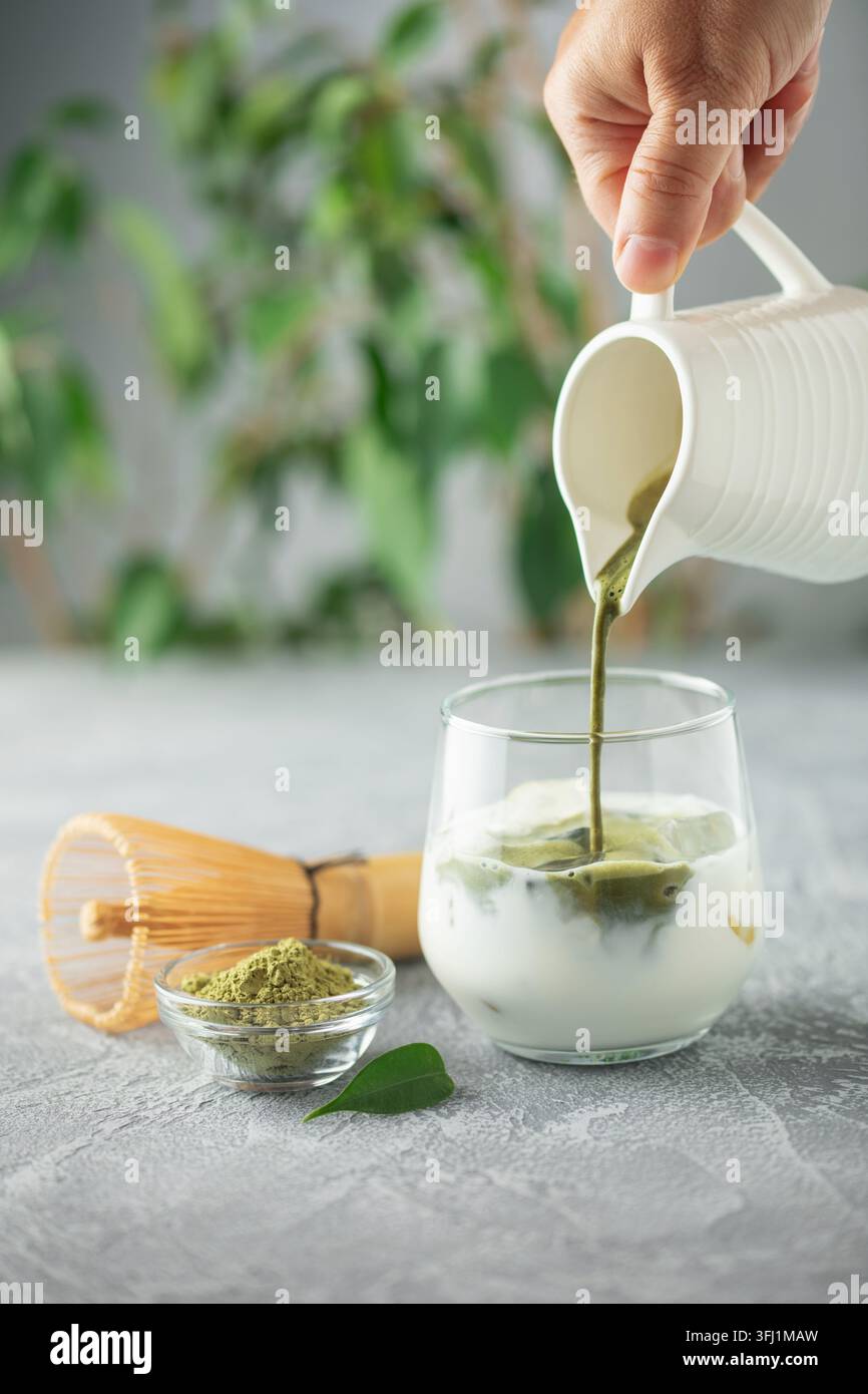Le thé Matcha est versé dans du lait glacé. Boisson végétalienne saine Matcha Latte Banque D'Images