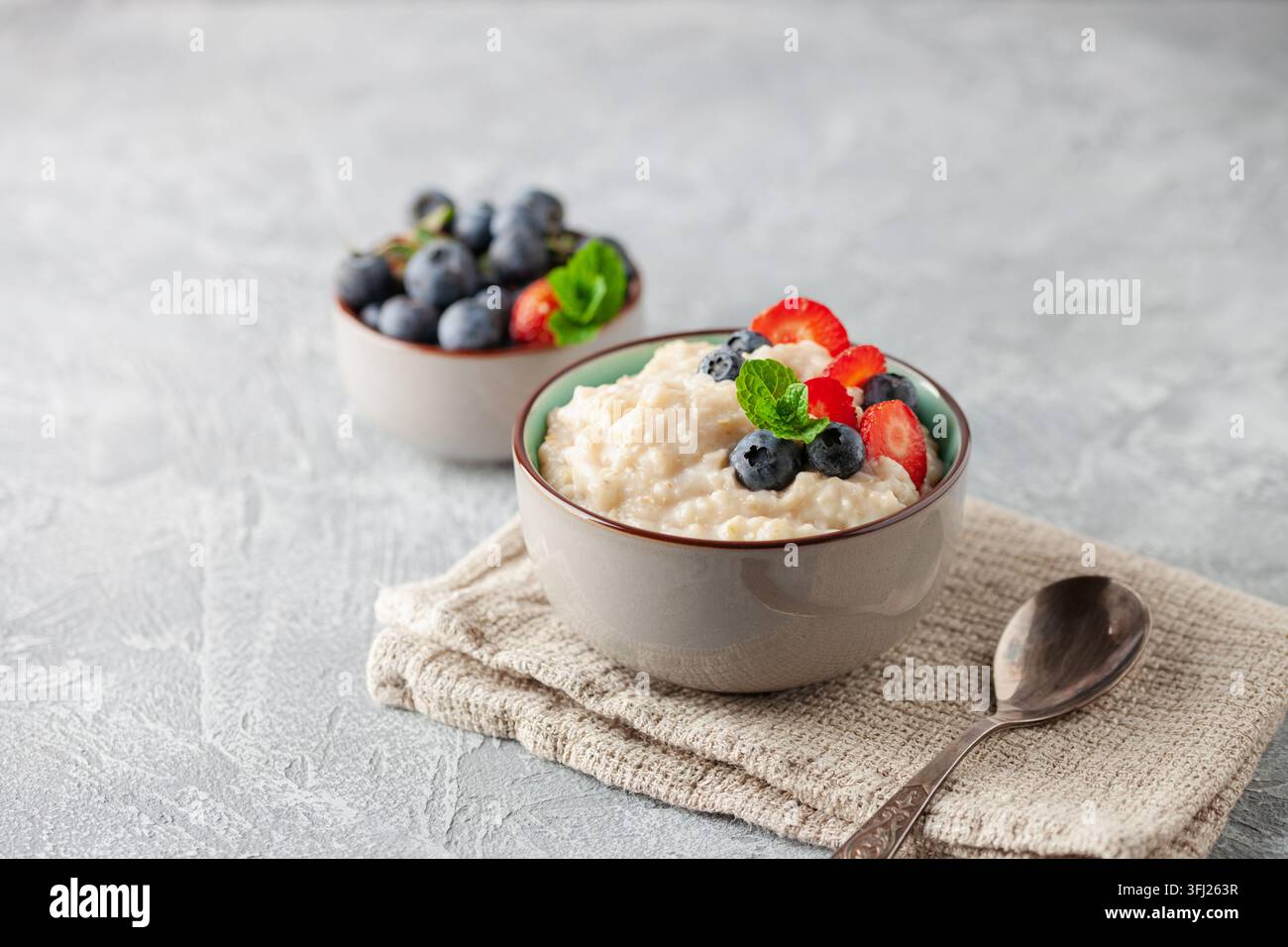 Bouillie d'avoine aux bleuets et fraises à la menthe fraîche dans un bol en céramique. Petit déjeuner sain Banque D'Images
