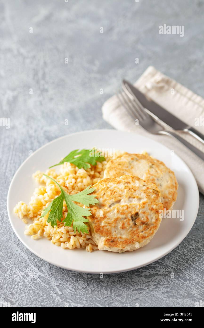 Escalopes de poulet ou de légumes avec un plat d'accompagnement de boulgour dans une assiette sur la table. Nutrition diététique Banque D'Images