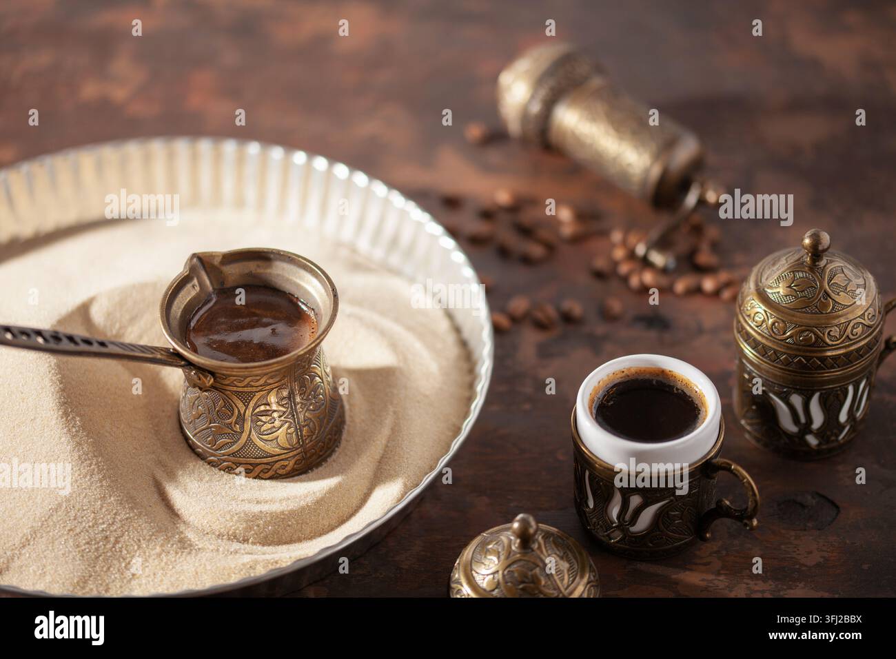 Café turc traditionnel au cezve préparé sur du sable chaud. Banque D'Images