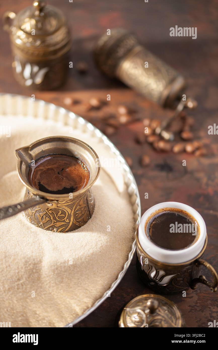 Café turc traditionnel au cezve préparé sur du sable chaud. Banque D'Images