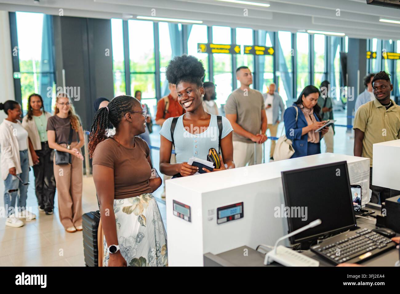 Divers amis souriant au comptoir d'enregistrement de l'aéroport Banque D'Images