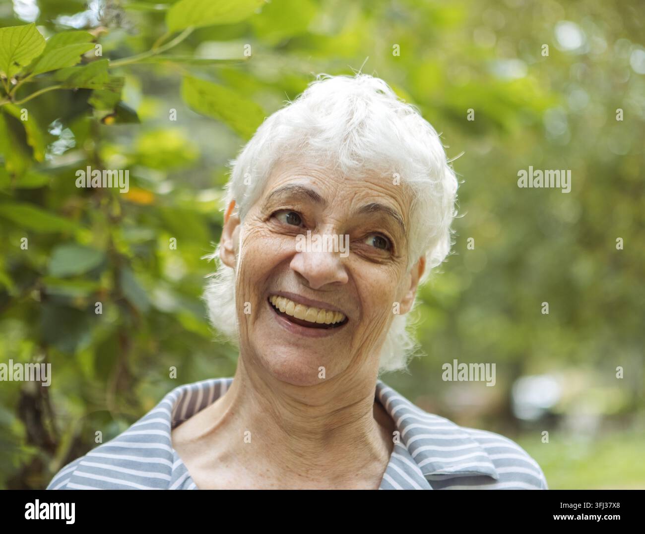 Portrait d'une femme âgée souriante dans un parc. Portrait en gros plan. Femme mûre heureuse et pensive se détendant en plein air. Banque D'Images