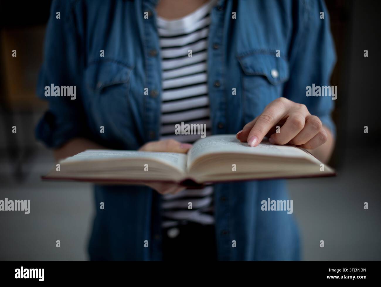 Femme tenant un livre en papier ouvert dans les mains, lisant un roman à succès, concept de librairie Banque D'Images