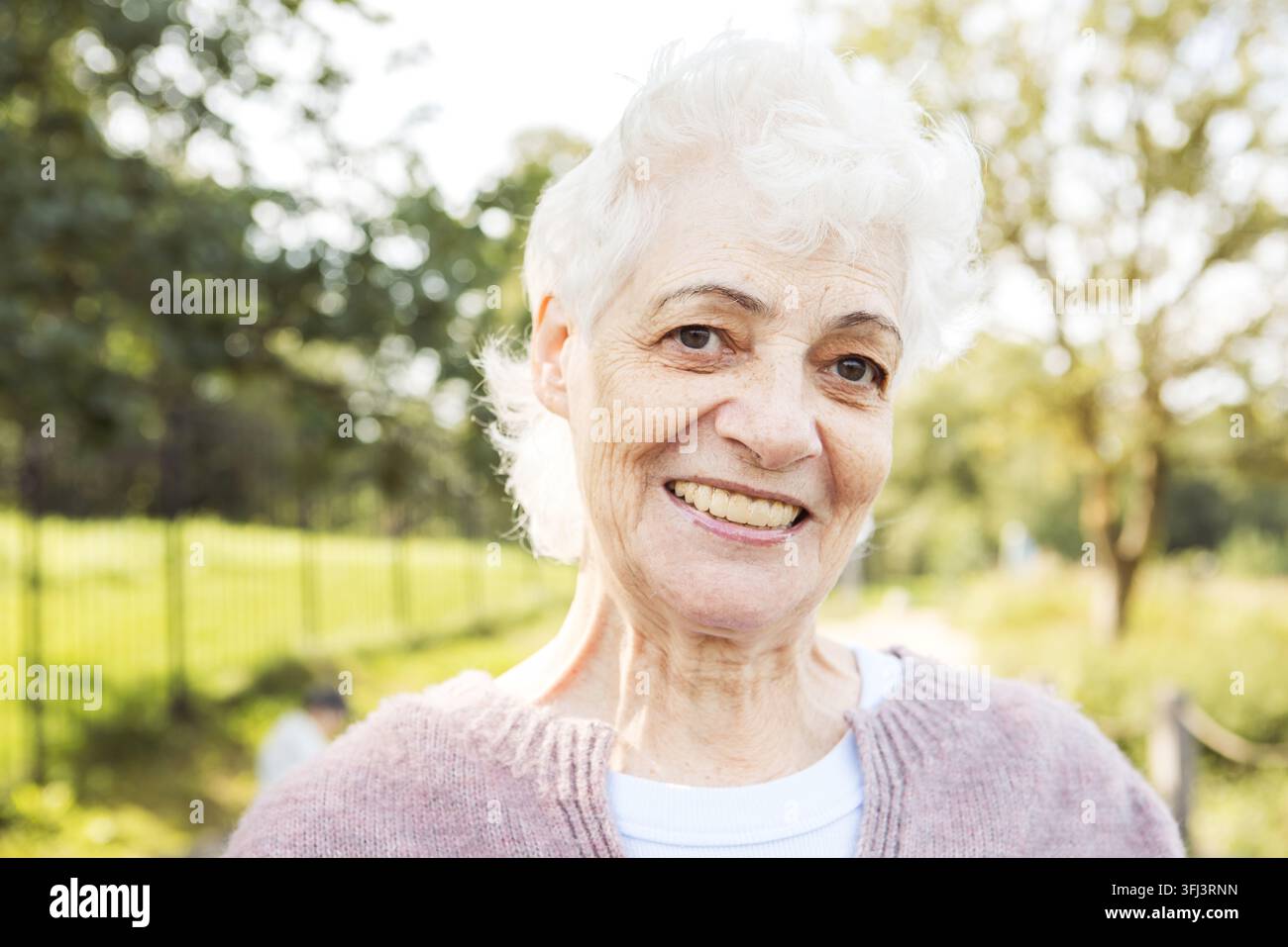 Portrait d'une femme âgée souriante dans un parc. Portrait en gros plan. Femme mûre heureuse et pensive se détendant en plein air. Banque D'Images