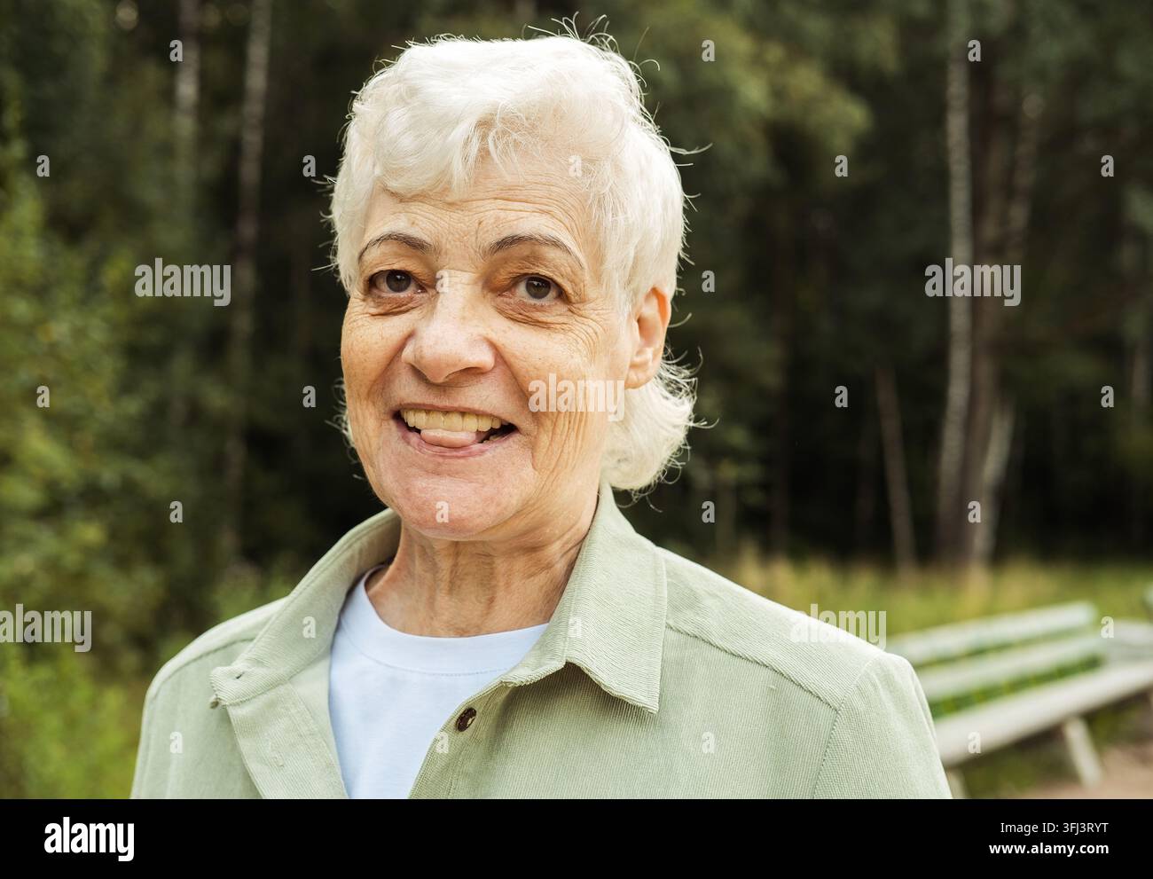 Portrait d'une femme âgée souriante dans un parc. Portrait en gros plan. Femme mûre heureuse et pensive se détendant en plein air. Banque D'Images