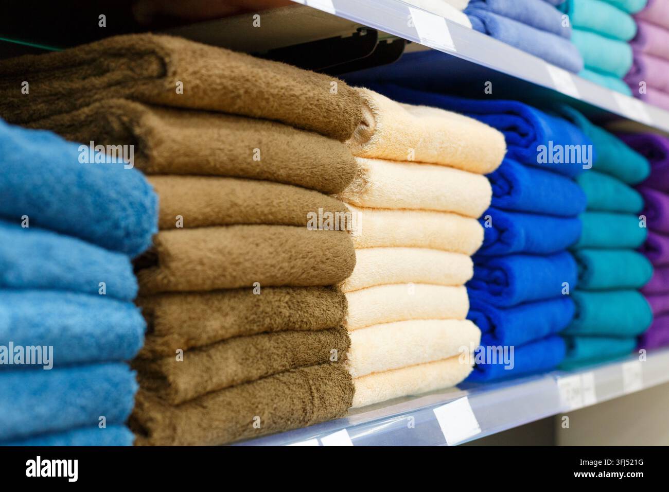 Rangées de serviettes pliées brun beige et bleu sur une étagère de magasin Banque D'Images