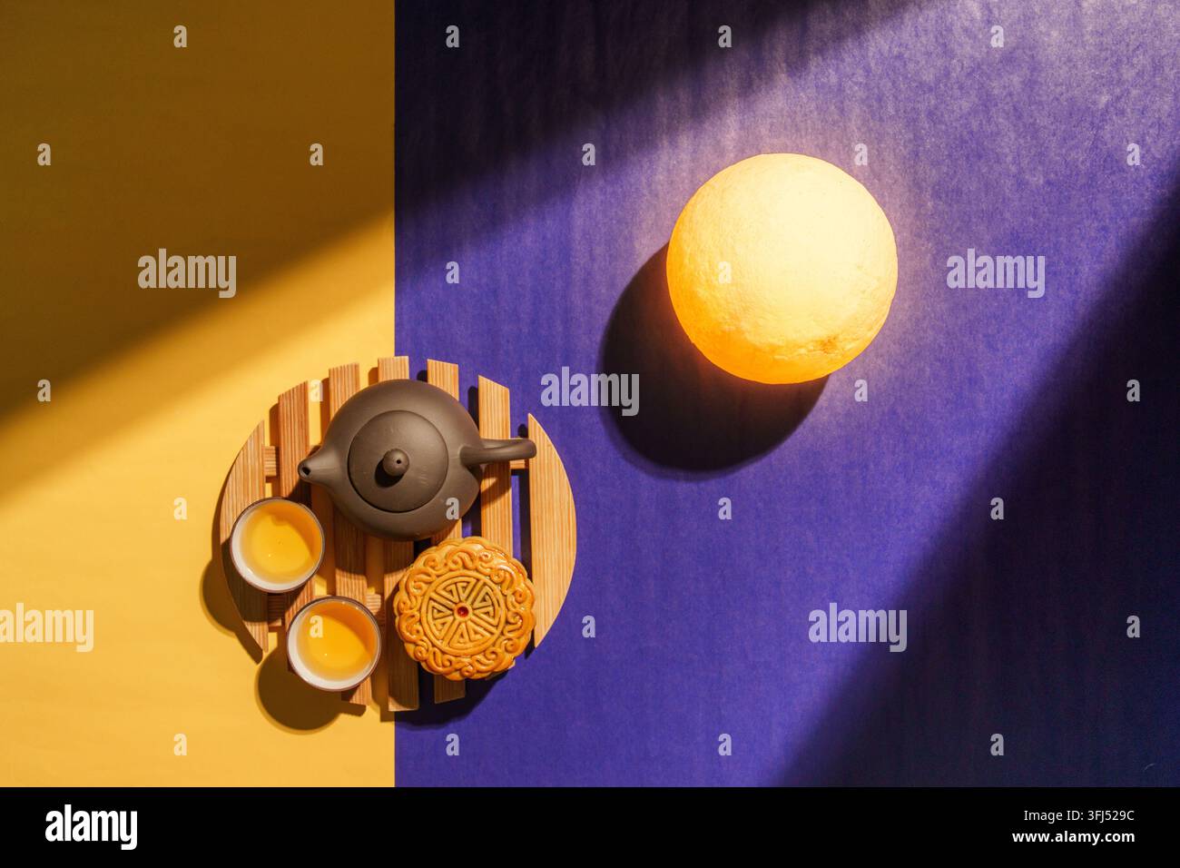 Mooncake avec théière en céramique et lampe lune lumineuse sur fond bleu et jaune Banque D'Images