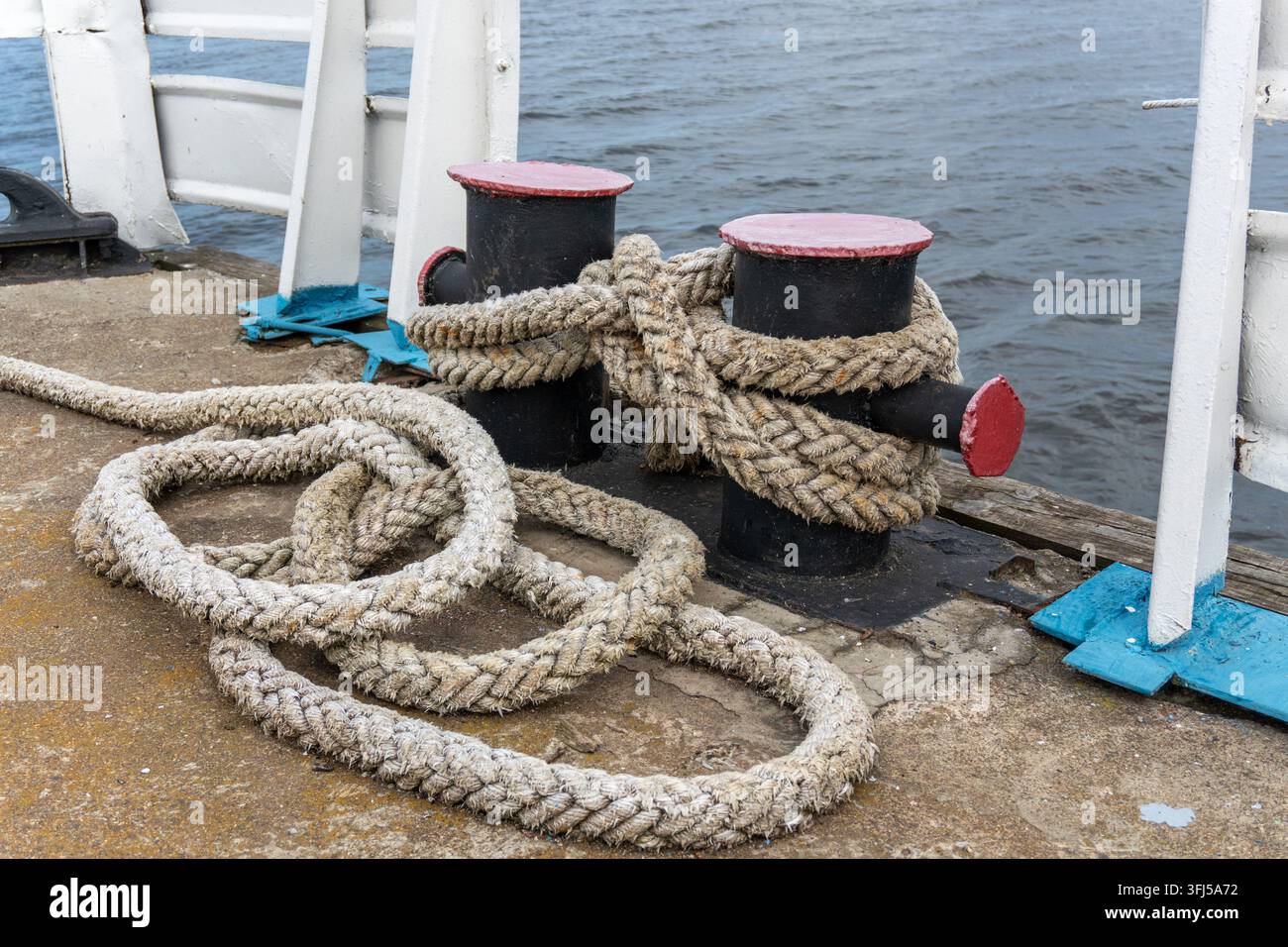 Boulon d'amarrage avec corde épaisse enroulée sur un quai en béton Banque D'Images