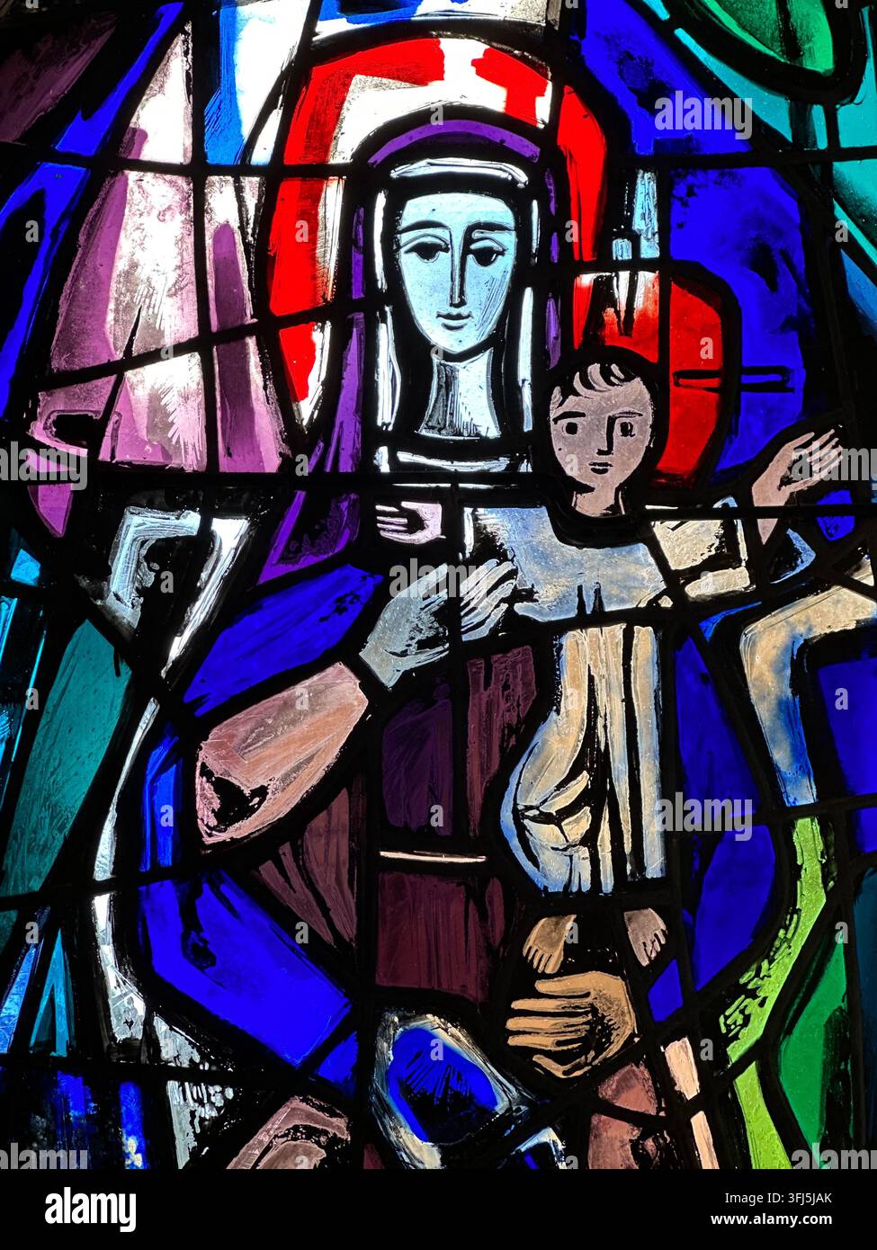 Vitrail coloré représentant la Vierge et l'Enfant. Œuvre d'art sur vitrail coloré représentant la Vierge et l'Enfant avec des bleus vibrants - Image de stock capturée avec un smartphone