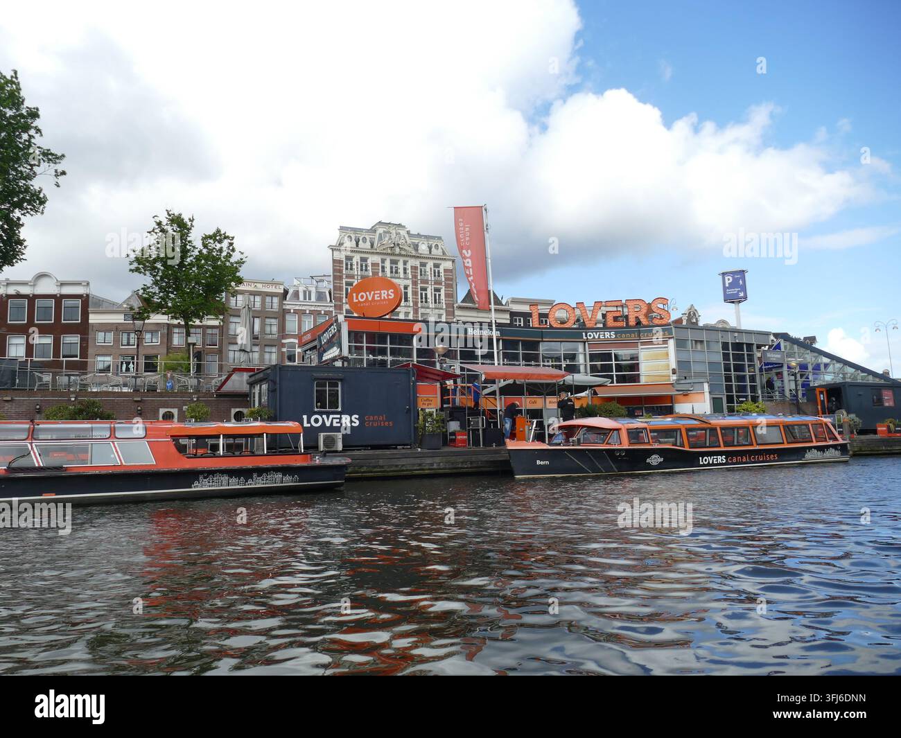 AMSTERDAM - 23 MAI 2025 - Les bateaux d'Orange Lovers Canal Cruises amarrés le long d'un cours d'eau historique, se préparant pour une excursion pittoresque en canal à Amsterdam Banque D'Images