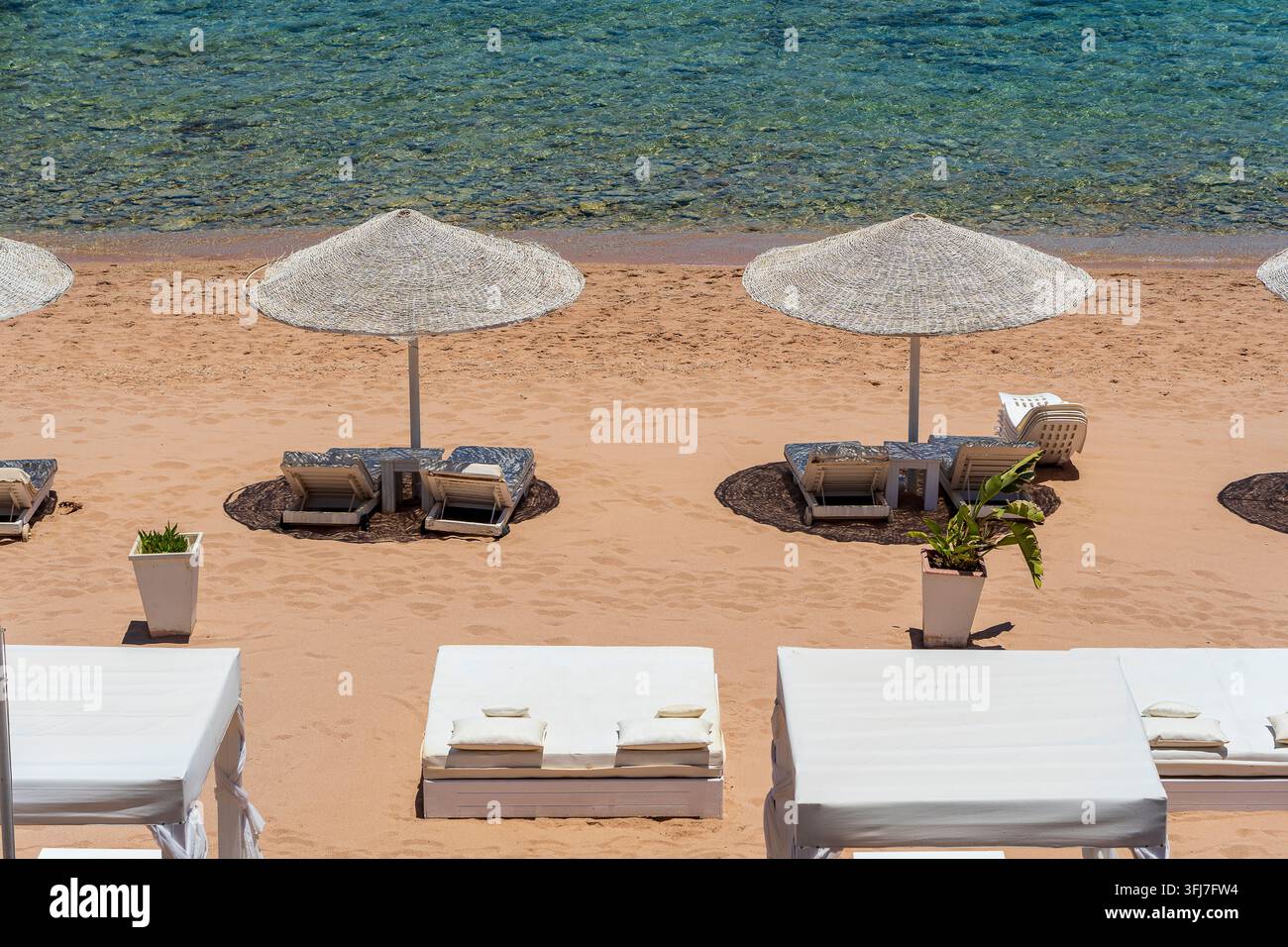 Plage de sable de luxe avec chaises de plage et parasols en paille blanche dans un complexe tropical sur la côte de la mer Rouge en Egypte, Afrique. Plages vides pendant la quarantaine Banque D'Images