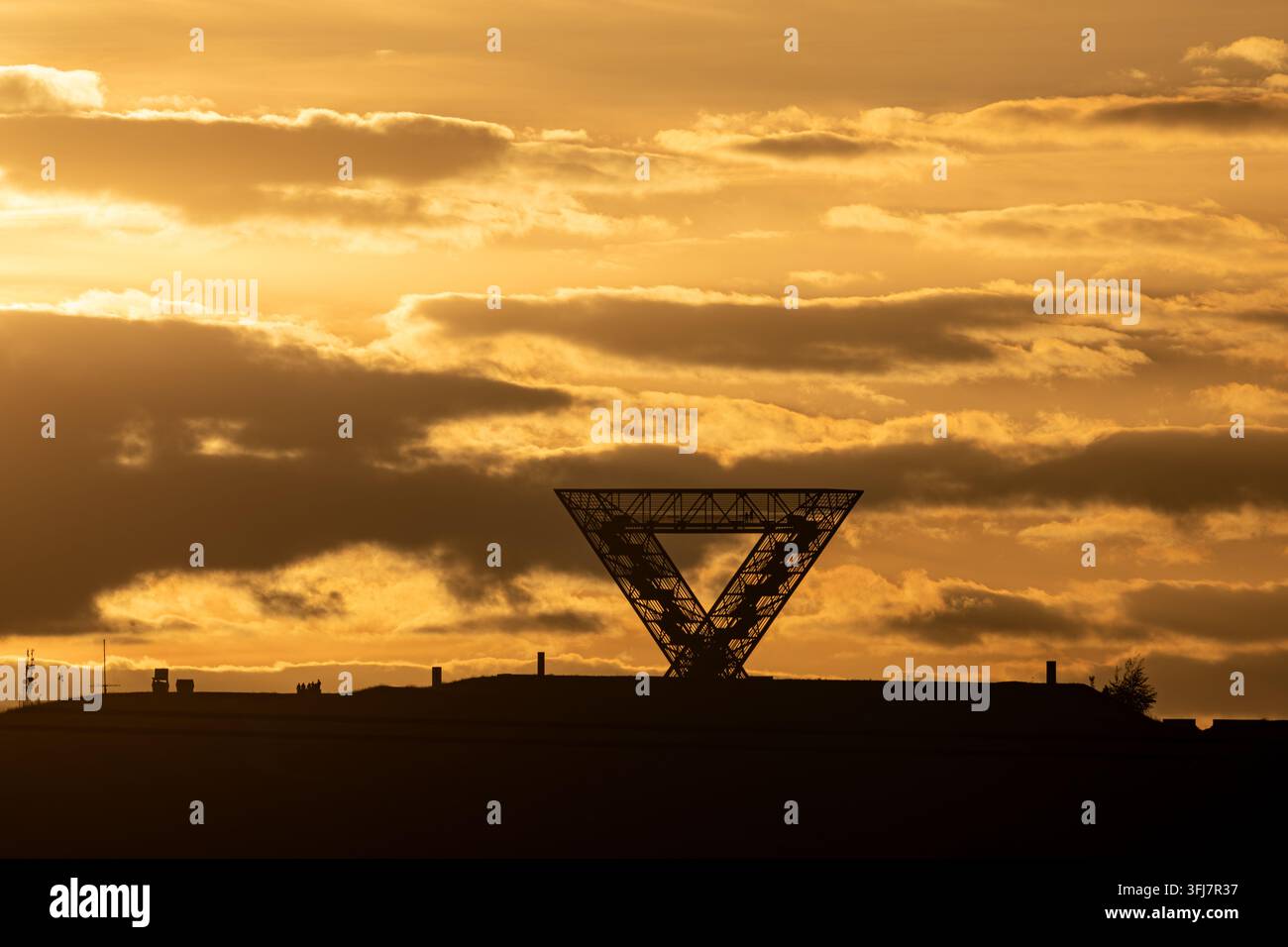 Silhouette du monument Saarpolygon sur un terril sous un ciel doré dramatique au coucher du soleil, Sarre, Allemagne Banque D'Images