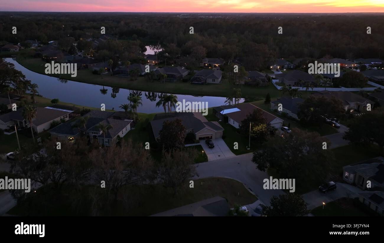 Réflexion des palmiers sur le lac privé d'un quartier de luxe en Floride. Plan large en plongée aérienne. Ciel doré et rose au lever du soleil. Quartier haut de gamme Banque D'Images