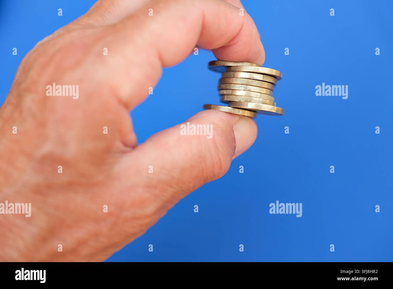 Petit tas de pièces tenu entre les doigts. Concept de finances personnelles, d'épargne et de budget. Minimaliste. Espace de copie. Profondeur de champ peu profonde. Banque D'Images