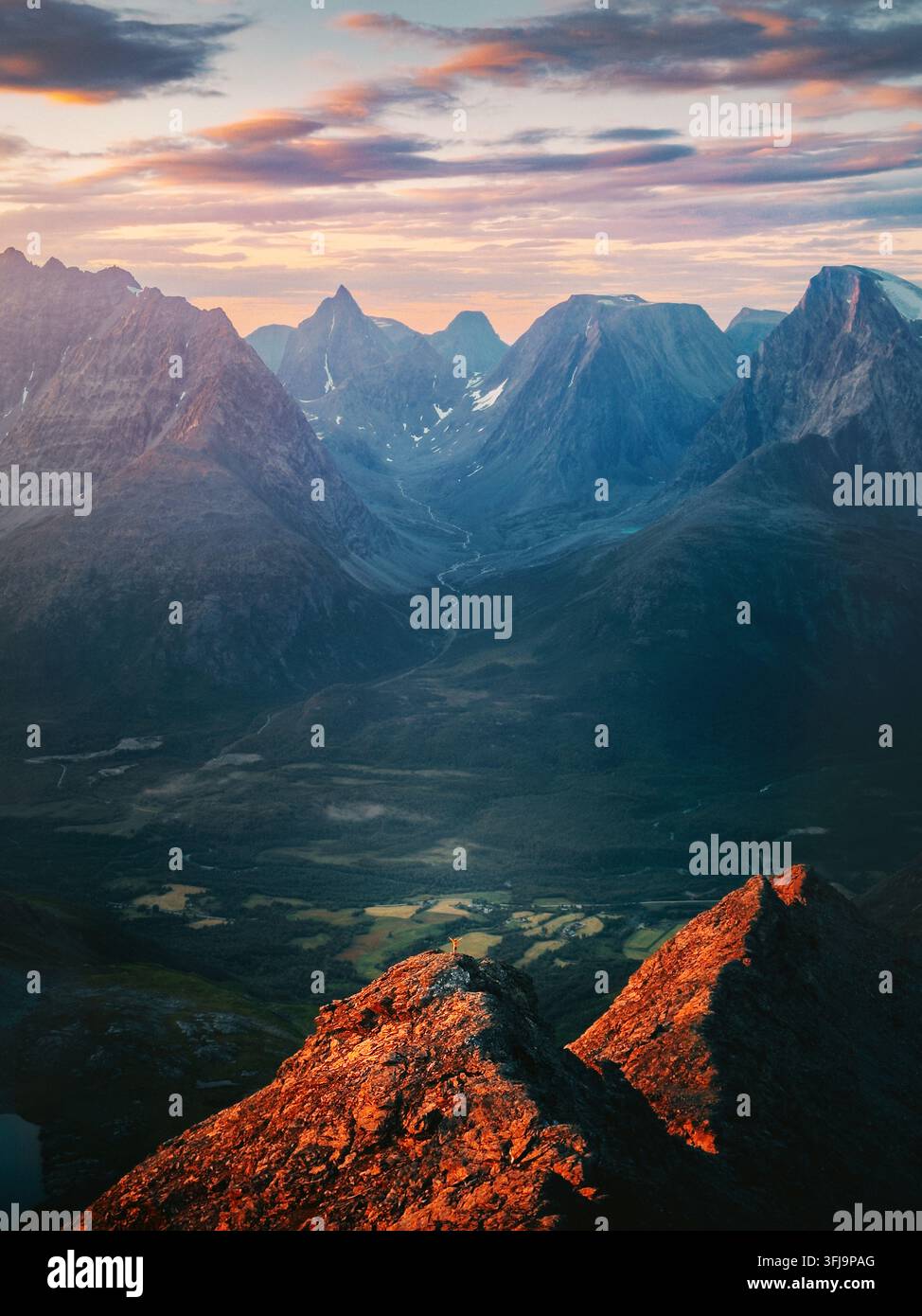 Montagnes au coucher du soleil en Norvège vue aérienne homme aventurier escaladant solo debout sur le sommet petit voyageur montrant l'échelle, vacances d'été actives vie saine Banque D'Images