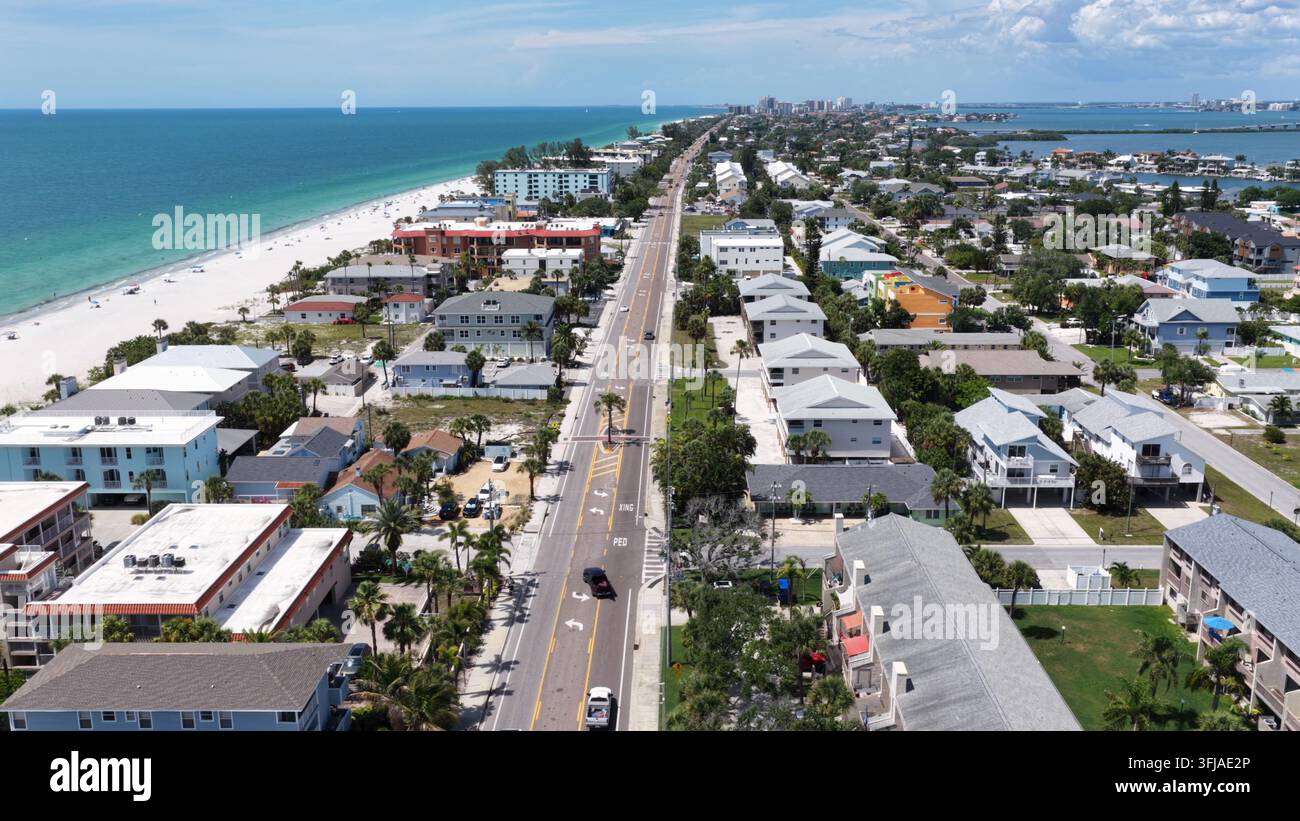 La route côtière passe entre les appartements en bord de mer et les eaux turquoise du golfe à Indian Rocks Beach, en Floride, les voitures roulent devant une plage de sable blanc près de C lointain Banque D'Images