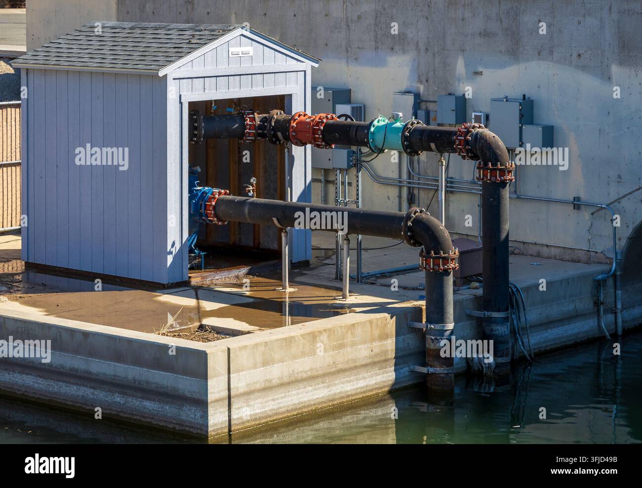Système de tuyauterie industriel d'eau en plein air avec un petit abri utilitaire à côté d'un plan d'eau dans le Sparks Marina Park, Nevada Banque D'Images