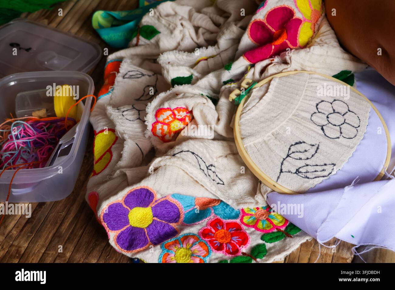 Un cerceau en tissu brodé, un espace de travail de l'art textile avec des fils colorés montrant des points floraux faits à la main et du matériel de couture Banque D'Images